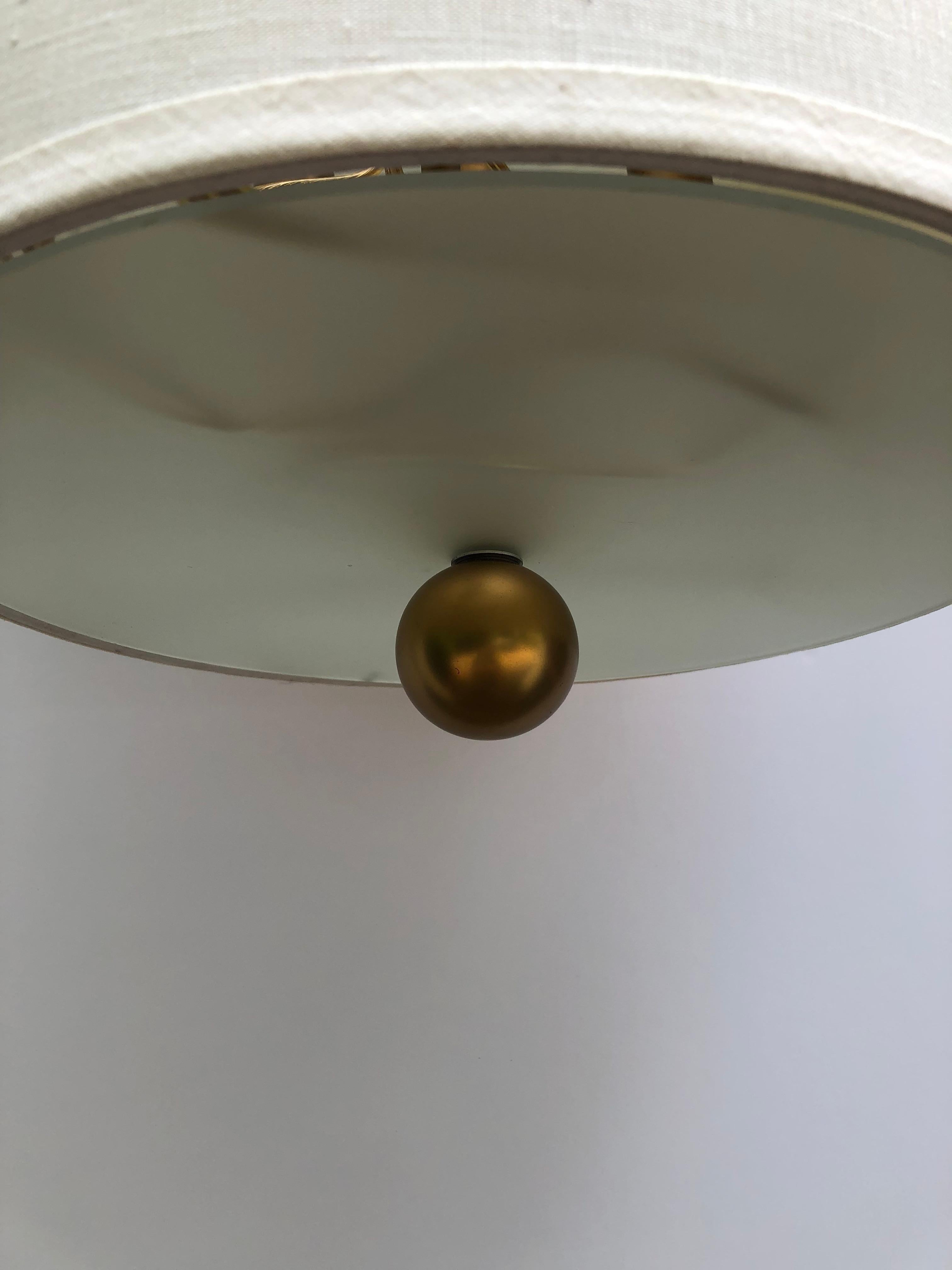 Contemporary stylish pendant chandelier having 3 gold balls in graduated sizes at the top and a sleek linen shade.