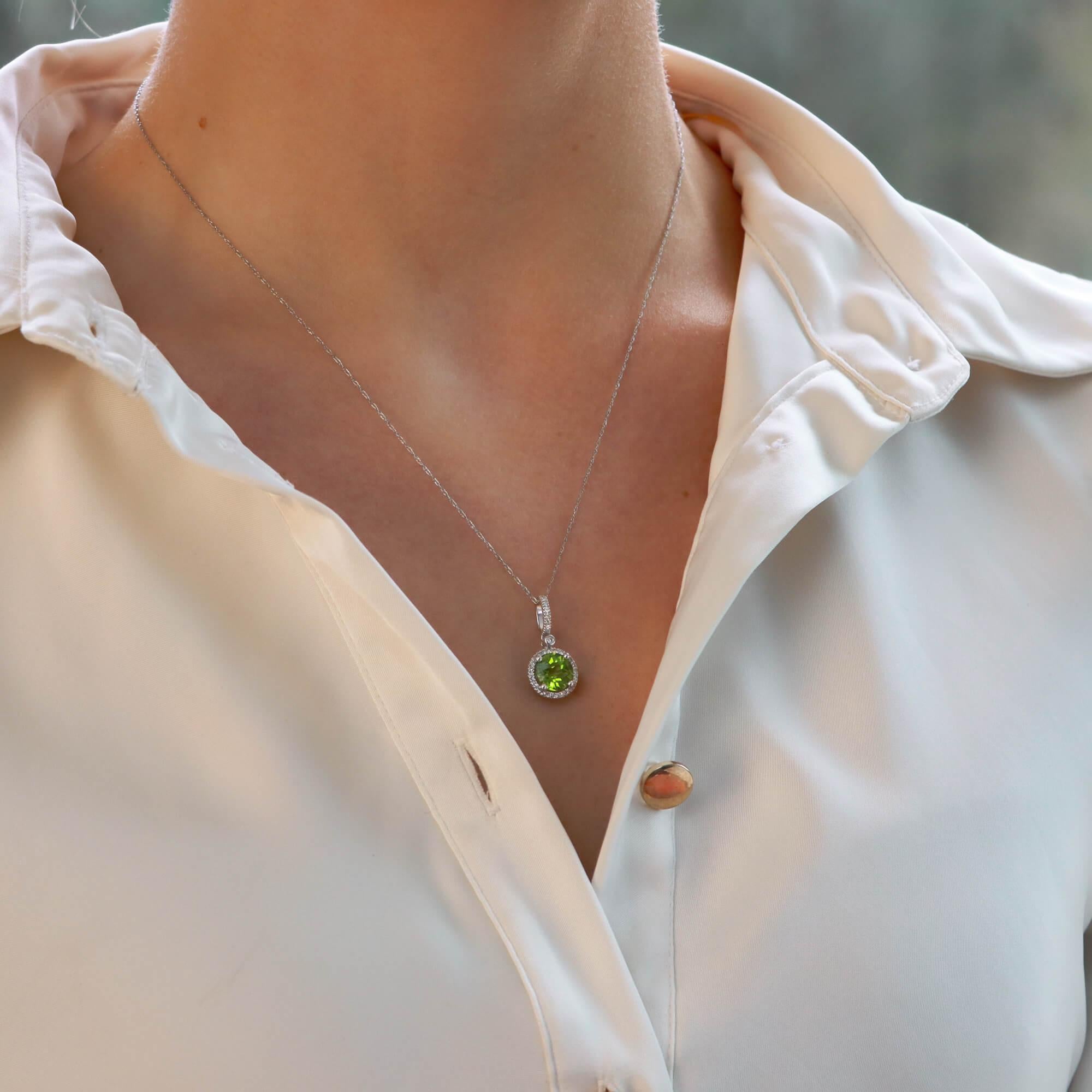 A beautiful contemporary peridot and diamond halo pendant necklace set in 14k white gold.

The pendant is predominantly set with a sparkly round checkerboard cut peridot, which is securely for claw set within a fine diamond set halo. The peridot