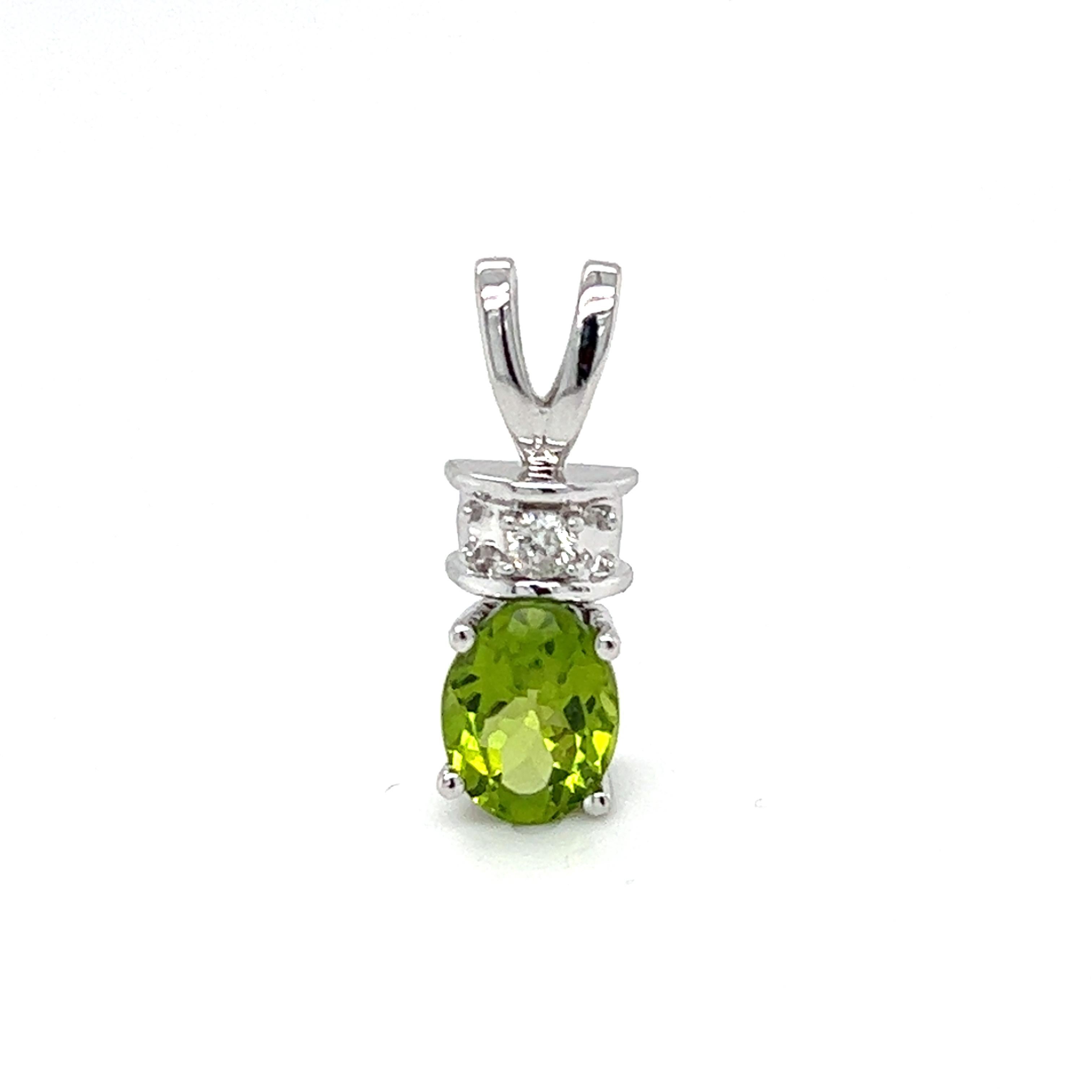 One 14 karat white gold pendant set with one 9x7mm oval green peridot and 0.10 carat total weight of brilliant cut diamonds with matching H/I color and I1 clarity.  The pendant measures 0.80