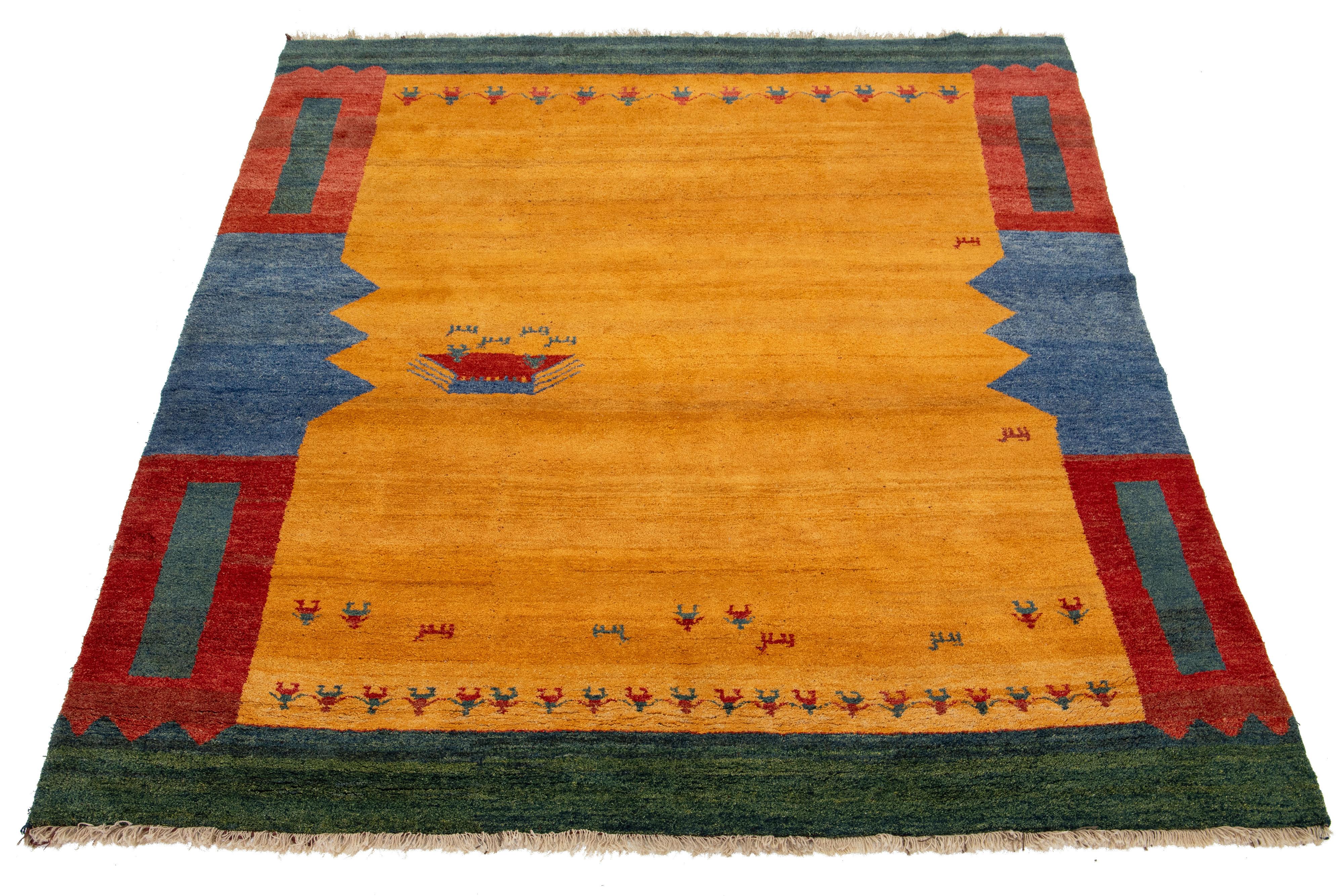 This modern Gabbeh rug is hand-knotted with a contemporary geometric pattern. The yellow base is accented with red, green, and blue details.

This rug measures 9'11