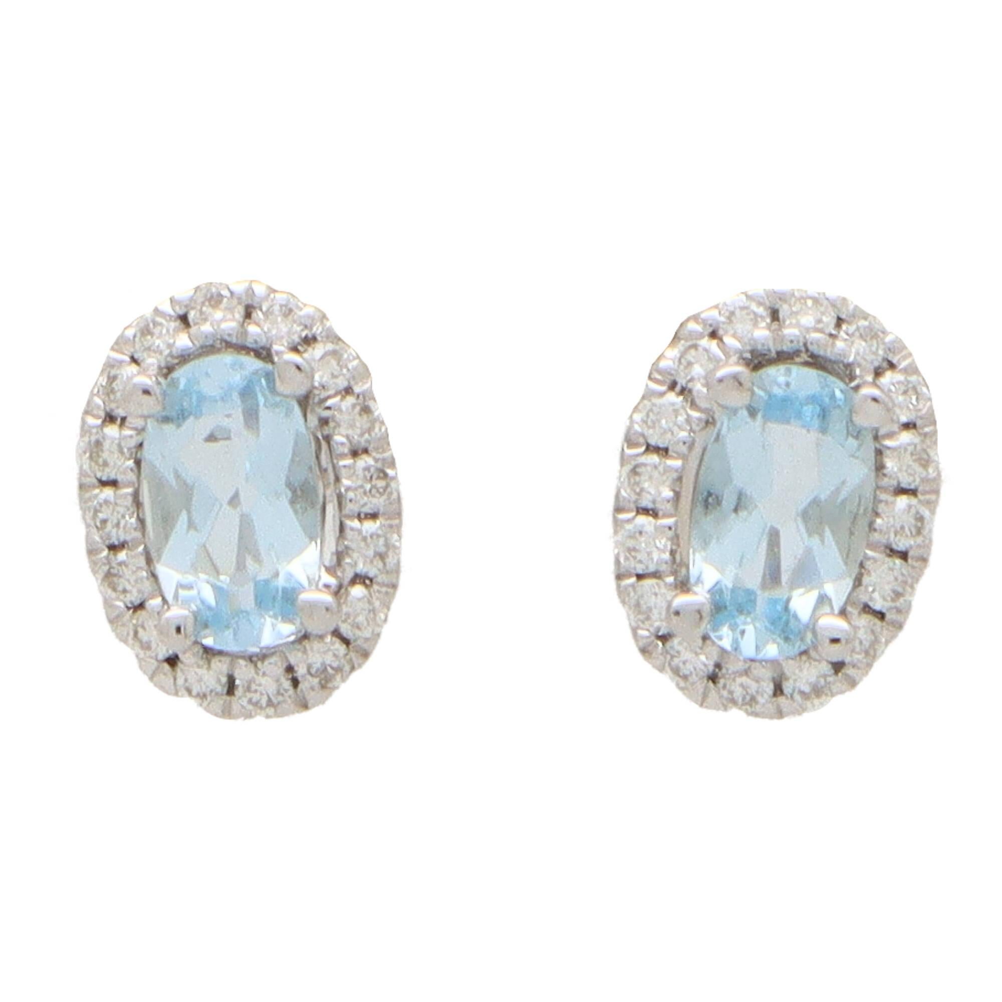 A lovely pair of aquamarine and diamond oval halo earrings set in 18k white gold.

Each earring centrally features a beautiful sky blue coloured oval shaped aquamarine surrounded by a halo of 16 round brilliant-cut diamonds. All of the stones are