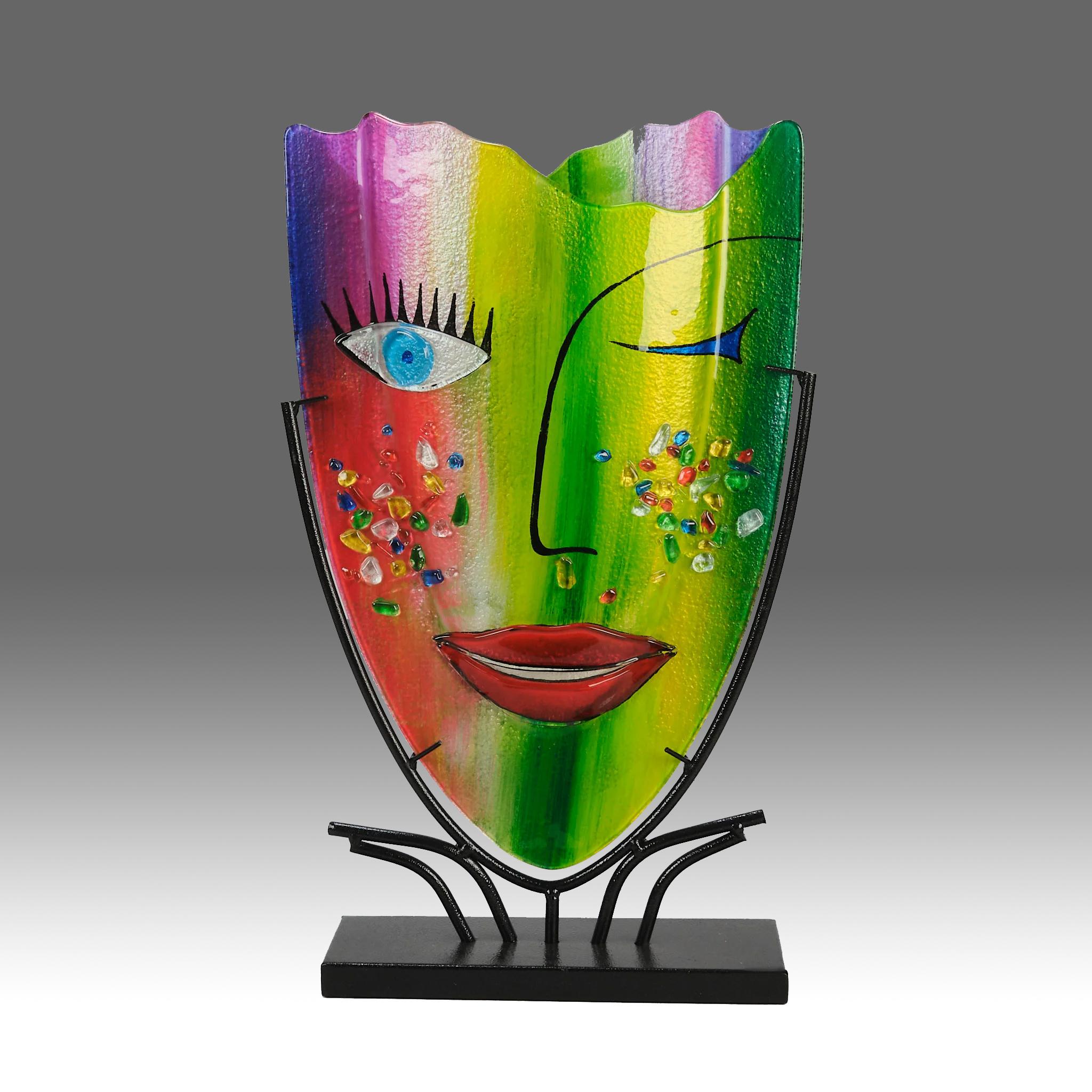 Un vivace vaso alto e modernista in vetro soffiato a mano con il disegno multicolore di un volto di donna con un occhio che ammicca, in omaggio al grande artista Pablo Picasso. Innalzato in un supporto in ferro battuto realizzato su misura. Una
