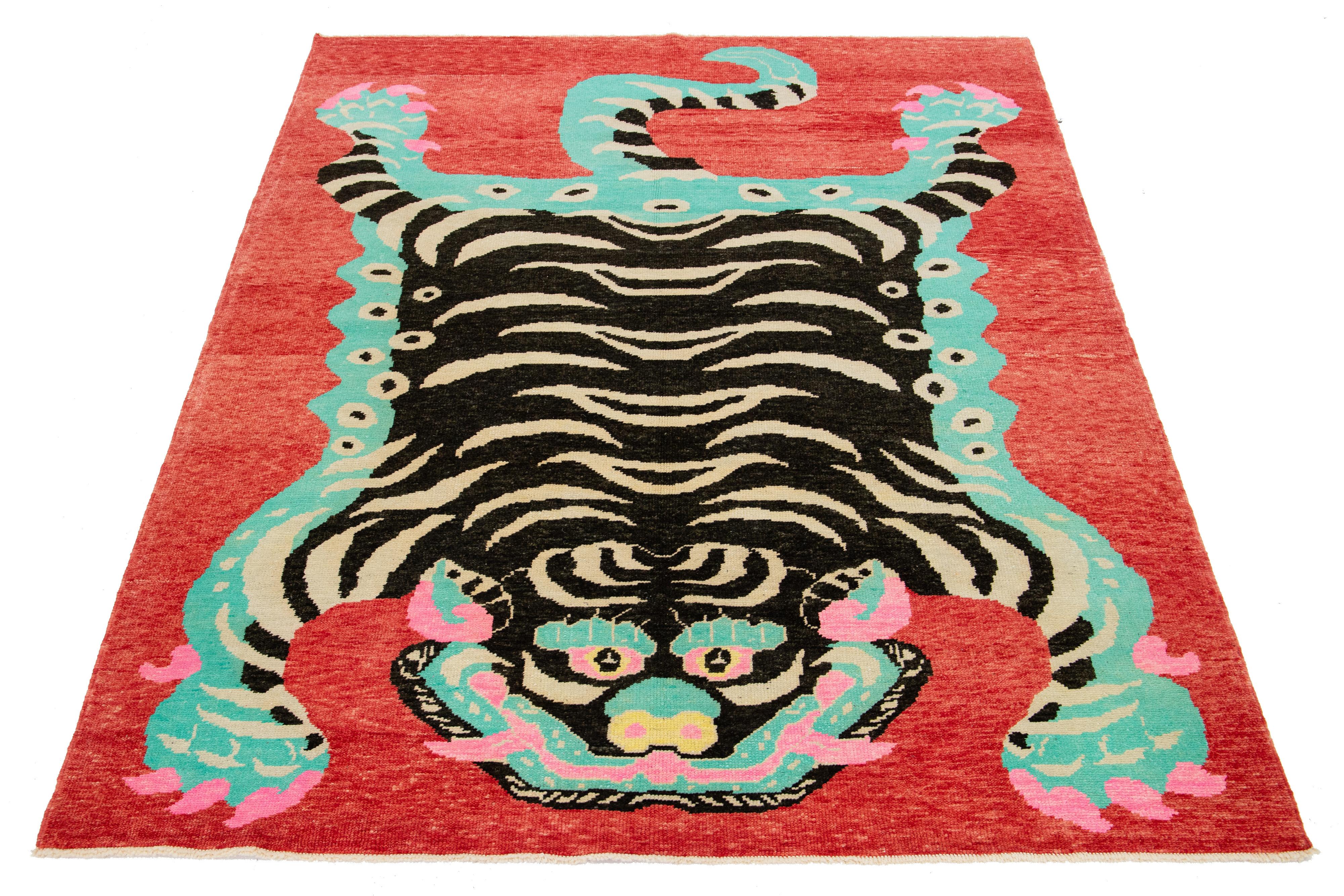 This beautiful handmade Turkish Art Deco wool rug has a red field. It features black, beige, pink, and turquoise accent colors in a stunning tiger pictorial design.

This rug measures 6'11