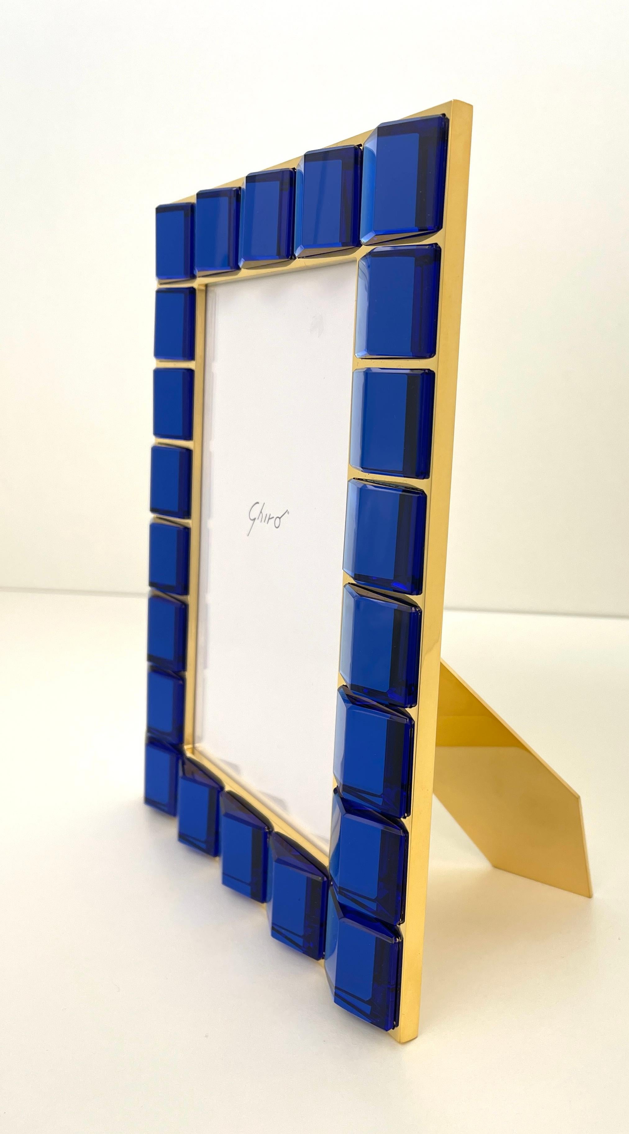 24 kt gold plated brass photo frame.
The frame is embellished with entirely handmade blue glass. Each crystal is set into the metal seat individually with extreme care and attention.
The shape of the glass, its intense and luminous color combine