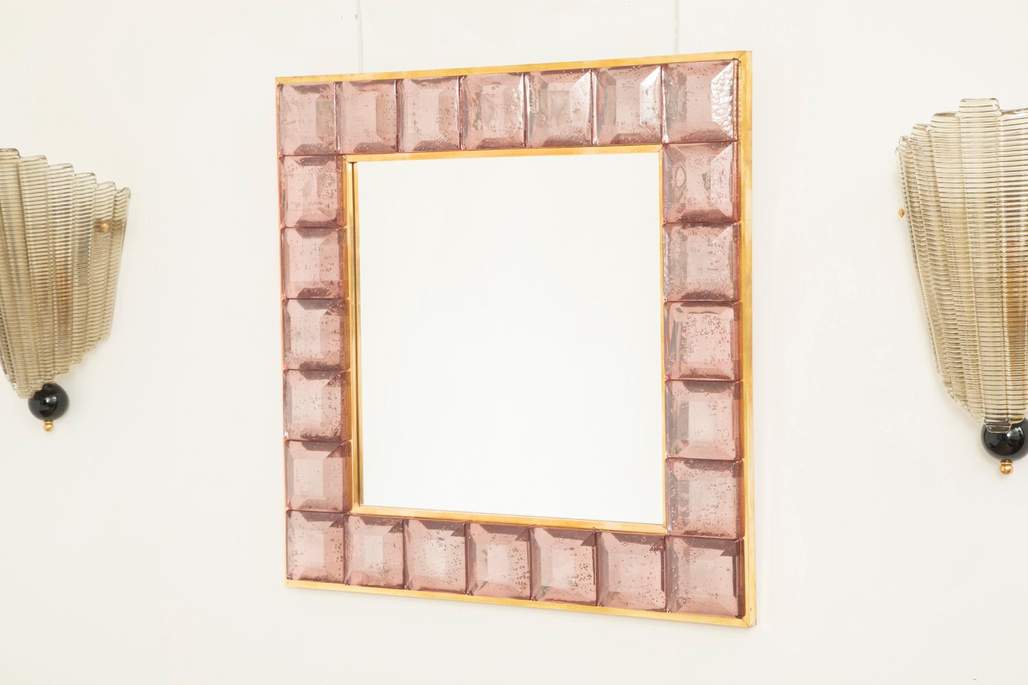 Miroir contemporain en verre de Murano, de forme carrée et rose, taillé en diamant.
Bloc de verre rose avec inclusions d'air naturelles dans l'ensemble du bâtiment. 
 Motif à facettes hautement poli
 Galerie de laiton
 Produits de luxe fabriqués à