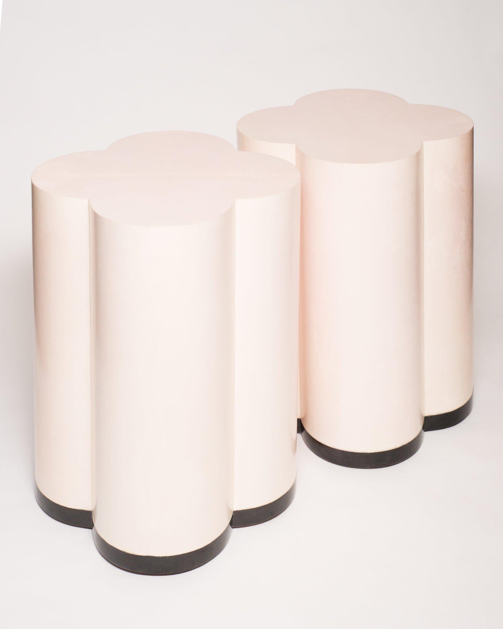 A pair of pale pink parchment leather clover drum tables/ottomans finished with black pen shell trim on a walnut base. Beautifully made, these tables/ottomans are delicate yet make a bold statement. Design wise, their gentle curves belong in any