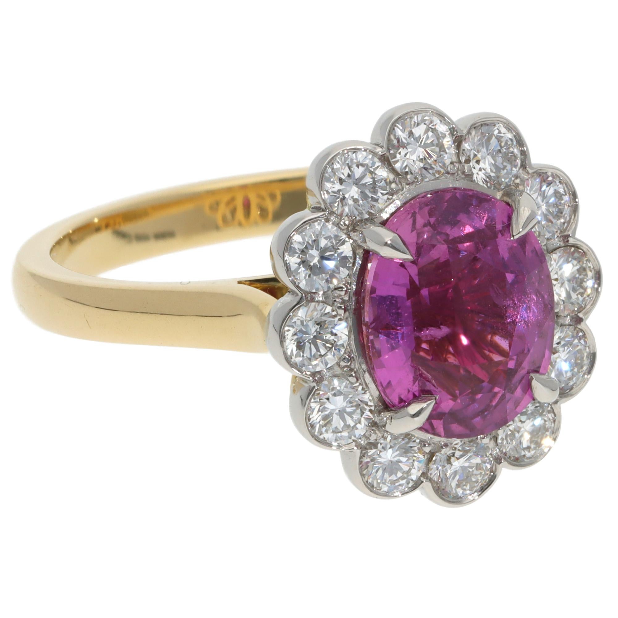 A beautiful contemporary pink sapphire and diamond cluster ring set in 18k yellow gold and platinum.

The ring features a vibrant oval mixed-cut pink sapphire. This pink sapphire is securely set with four claws in an open-back platinum setting. It