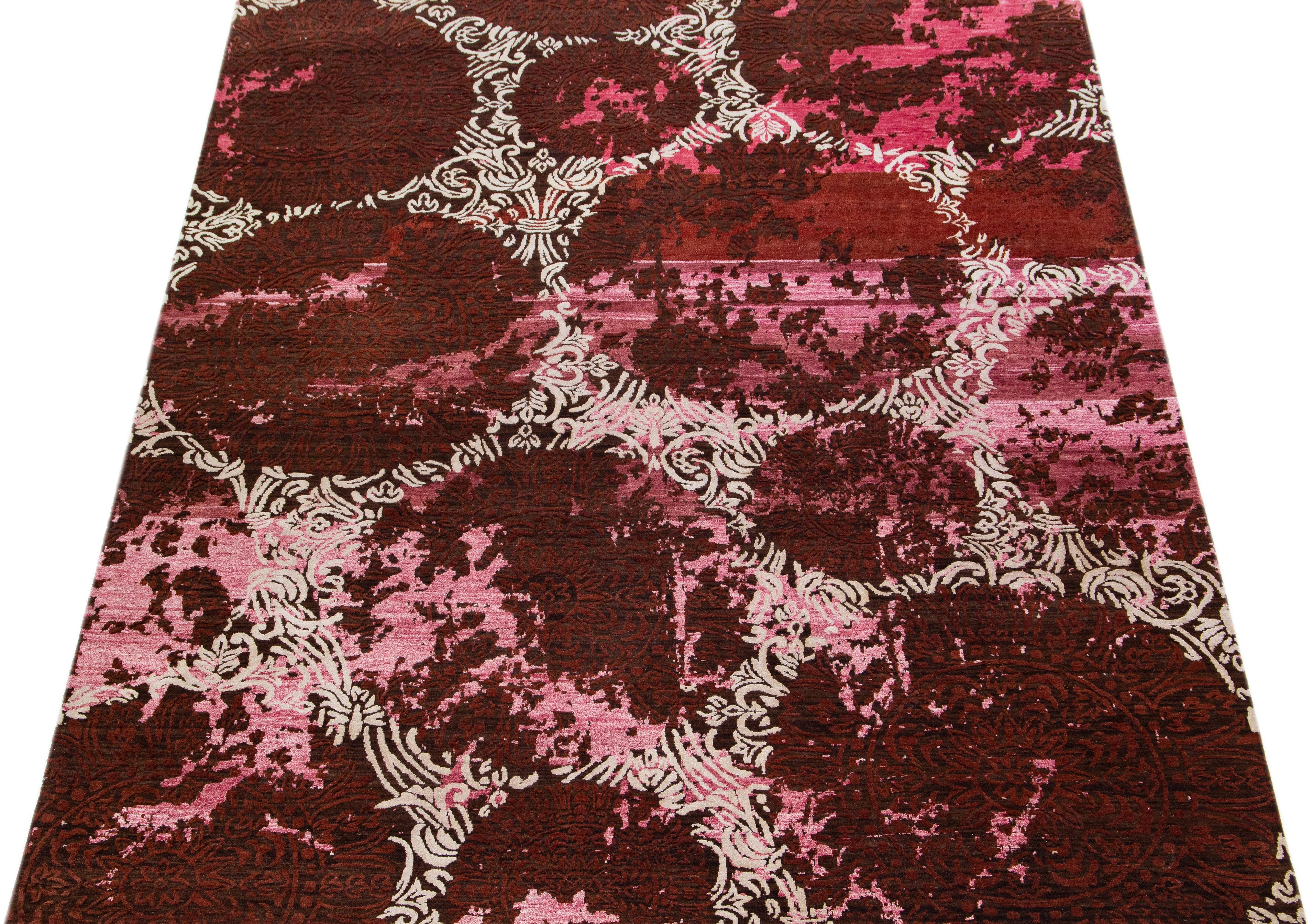 Beautiful modern Tibetan Indian wool & silk rug with the pink field in an abstract patterning ivory and burgundy color. This combination of materials offers strength and durability for everyday use, and its intricate design adds a touch of elegance