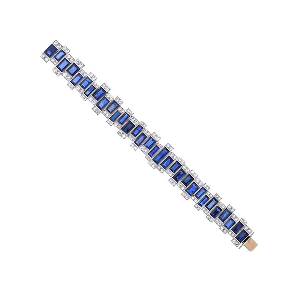 A contemporary geometrical bracelet designed as an asymmetric line of sapphires with diamond borders. Composed of 31 baguette-cut sapphires of different sizes each accented by 2 circular-cut diamonds to the top and bottom. The total weight of