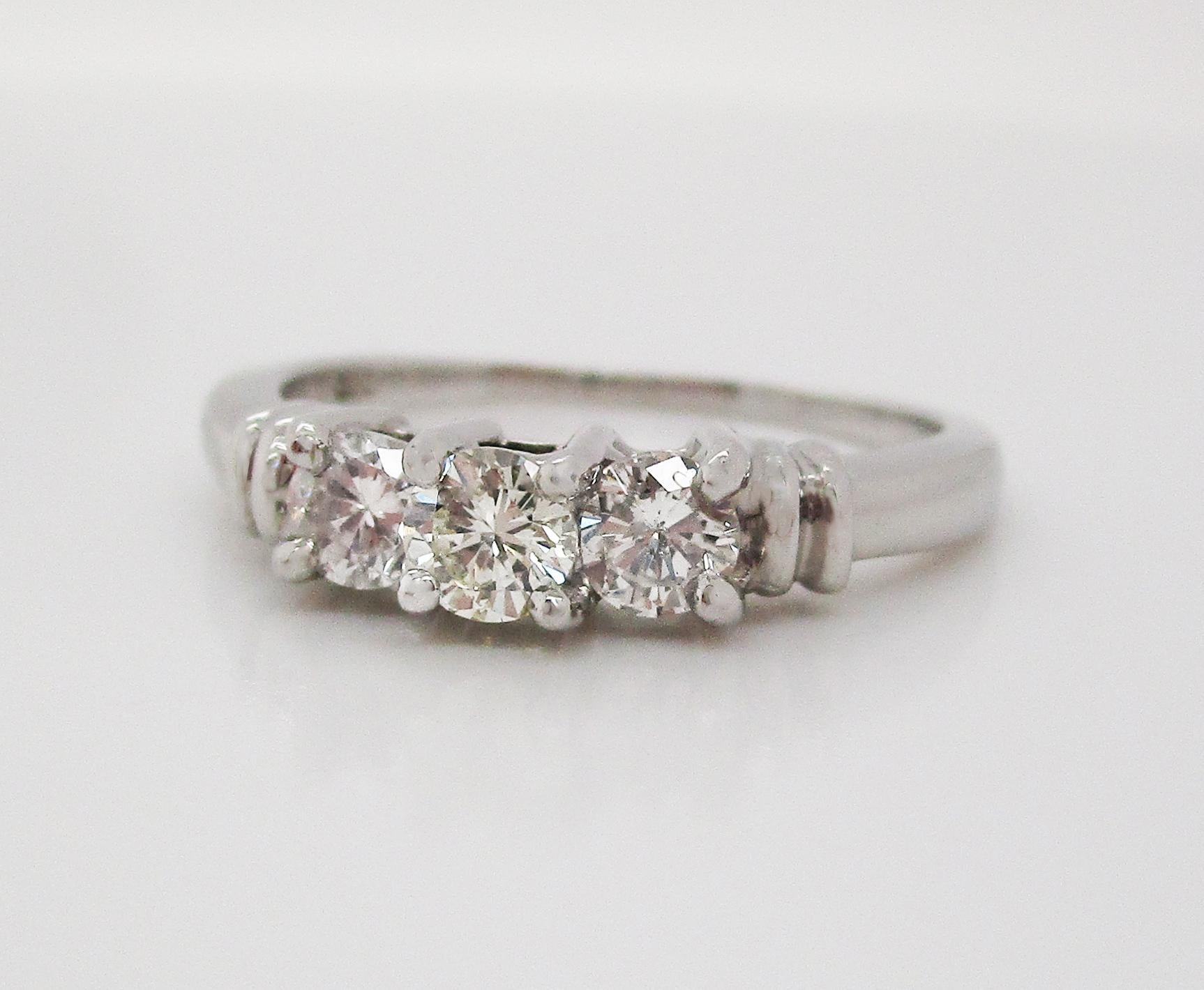 This gorgeous three stone diamond engagement ring is in bright white platinum and has a gorgeous contemporary look! The three diamonds in this ring are set in a stepped design with an architectural under-gallery. The stepped design of the ring