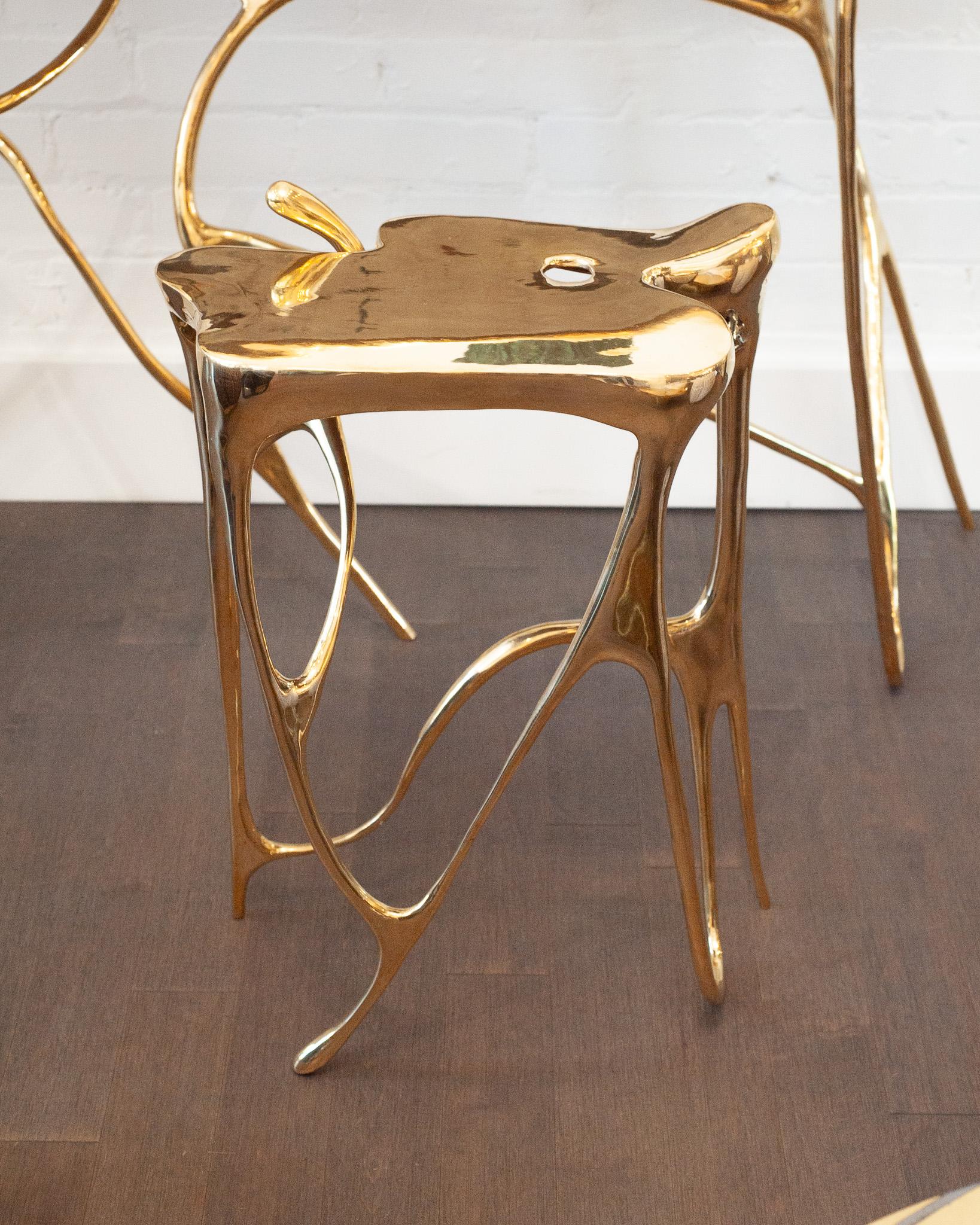 Table d'appoint sculpturale en laiton - Avec son plateau en laiton poli soutenu par une base aux lignes fluides et tourbillonnantes, cette table d'appoint haute respire à la fois la luminosité et le mouvement. Ses surfaces réfléchissantes amplifient