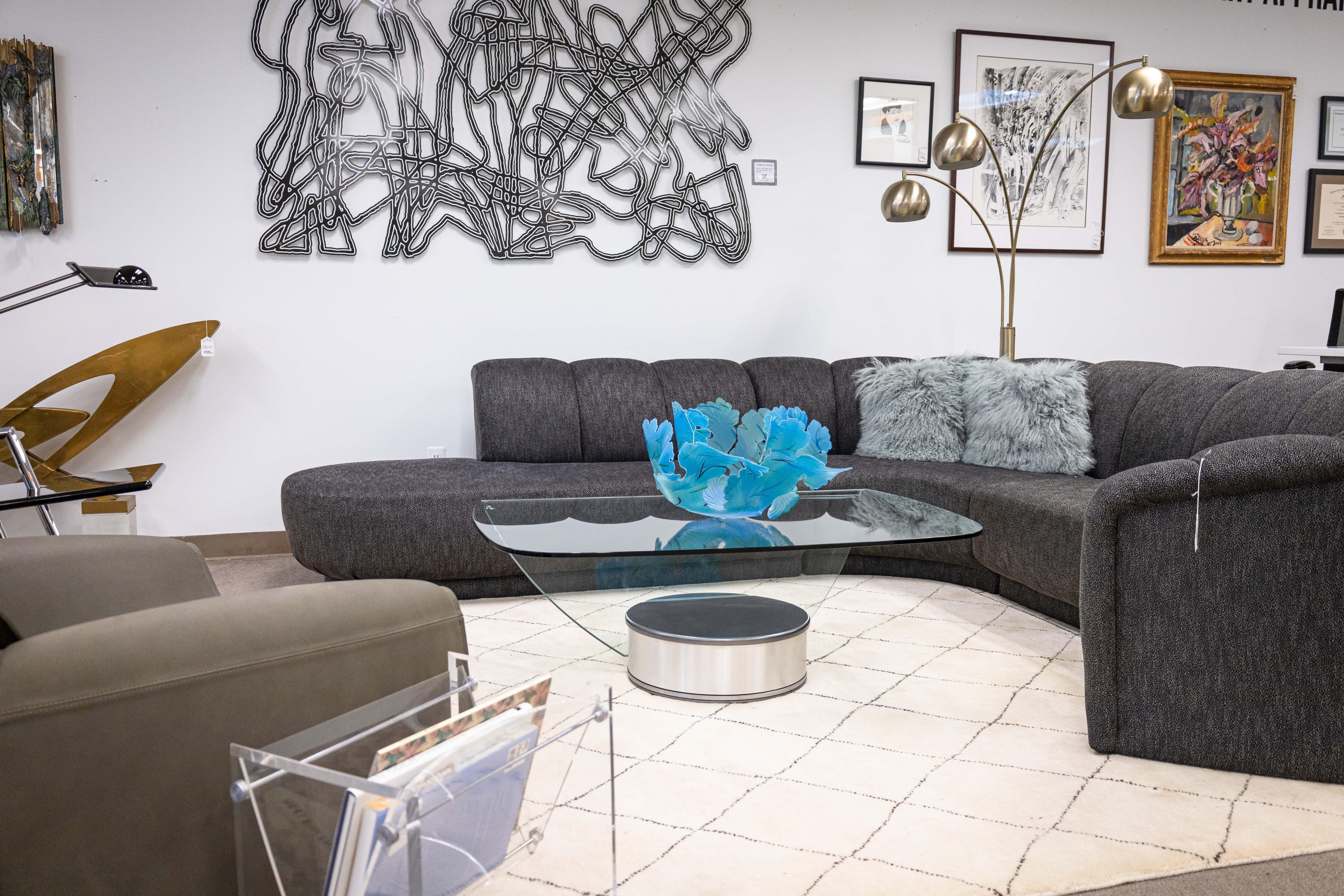 A postmodern Brueton style swivel coffee table. This is a beautiful contemporary coffee table featuring a modern selection of materials in chrome metal and glass. The base of the table features a round base with a combination of brushed metal and