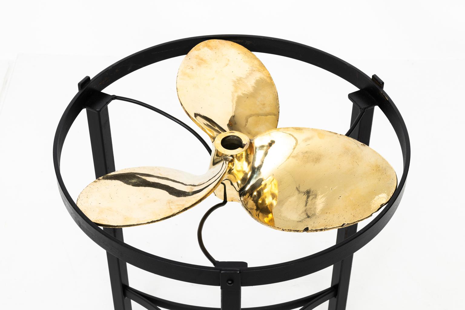 Contemporary brass and glass top side table in a black painted finish. It features a Victorian era brass boat propeller from circa 1880 repurposed as an accent. Please note of wear consistent with age including wear to the propeller.