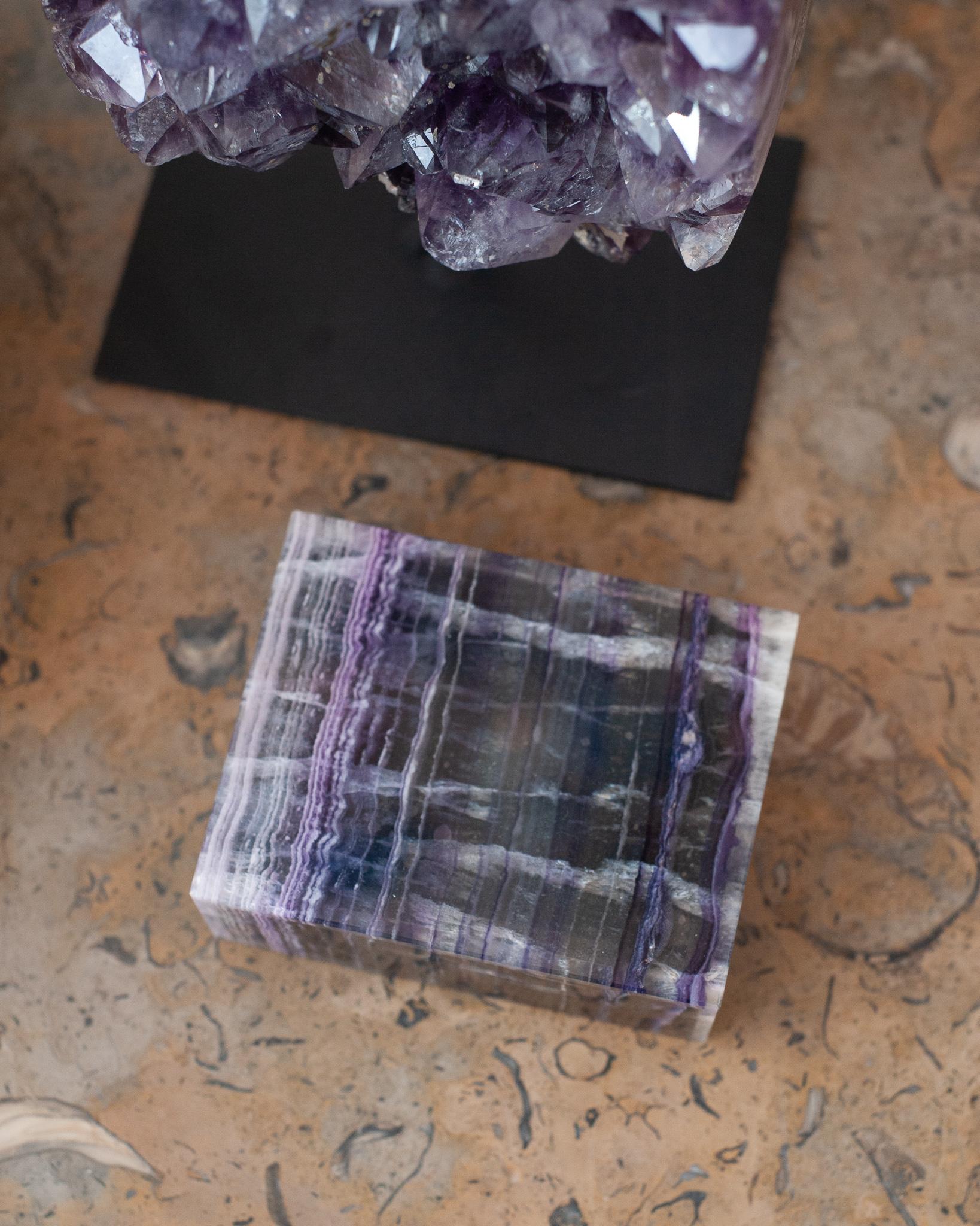 Invite healing energy into your home with this exquisite purple and clear fluorite box. This box is beautifully made with a hinged lid and expert construction. Lined in black velvet with black marble trims. Finished to a high polish to show off the