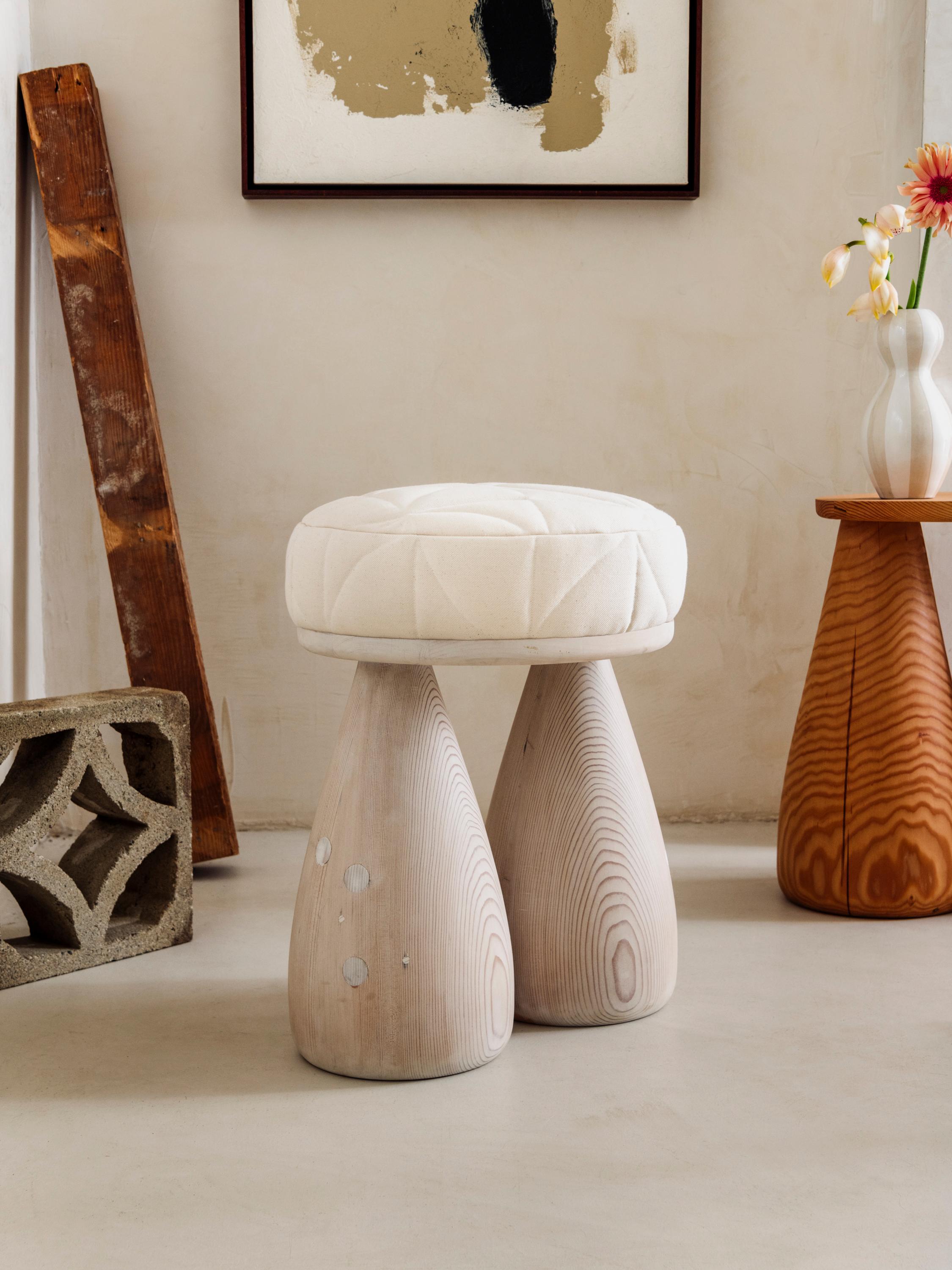 As part of Studio Sam Klemick's second collection The Quilted Cutie Stool debuted originally in 2023. The hand built wooden stool is made in Los Angeles California. The seat has be upholstered with hand quilted canvas. Signature Bell shaped legs