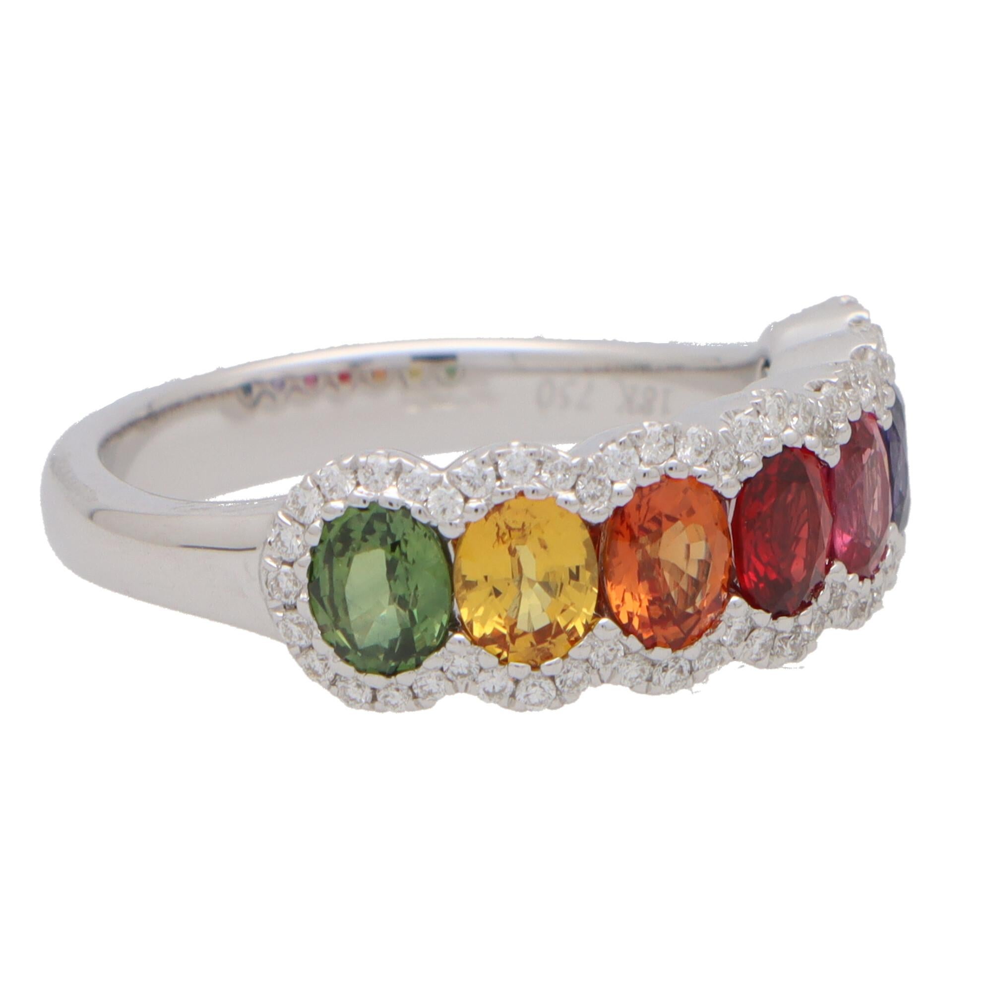 A beautiful rainbow sapphire and diamond half eternity ring set in 18k white gold.

The ring is firstly composed of seven oval cut sapphires that beautifully descend through the colour spectrum. The sapphires are securely micro-claw set and