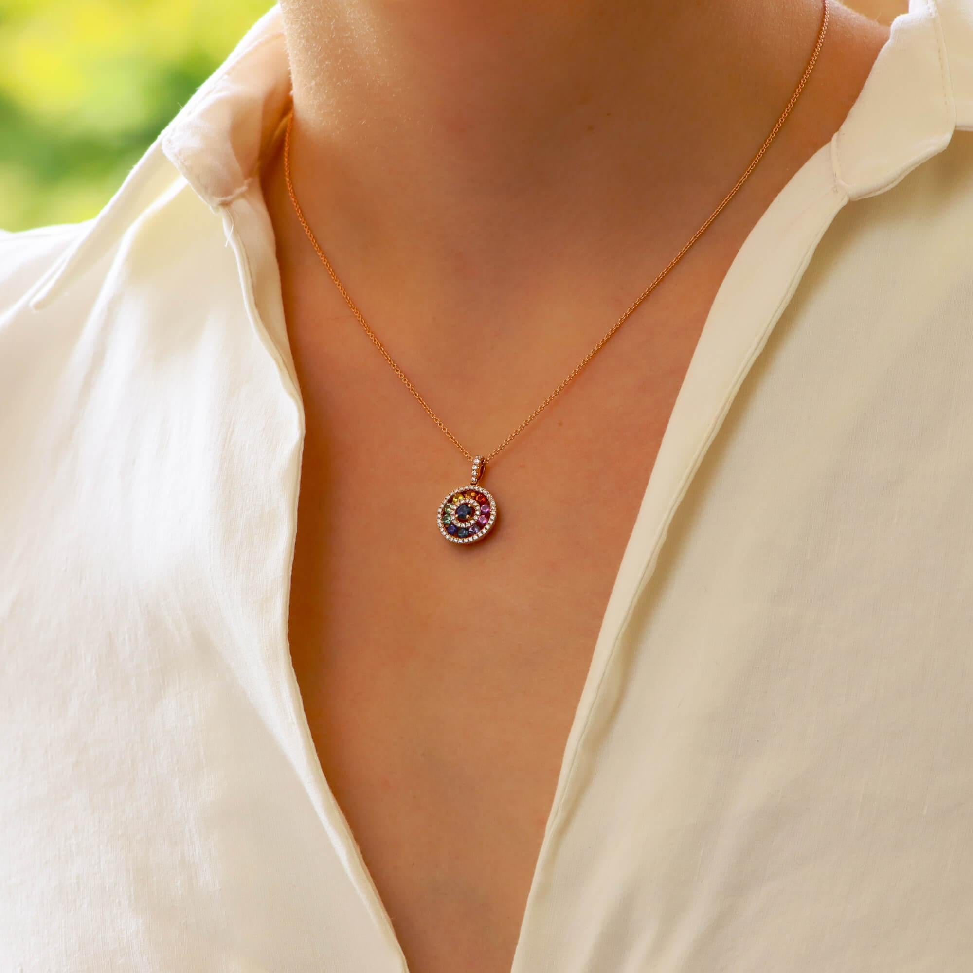An elegant rainbow sapphire and diamond circle pendant set in 18k rose gold.

The pendant depicts a circle motif, set with a ring of round cut rainbow sapphires. These sapphires are bordered by round brilliant cut diamonds which enhance the