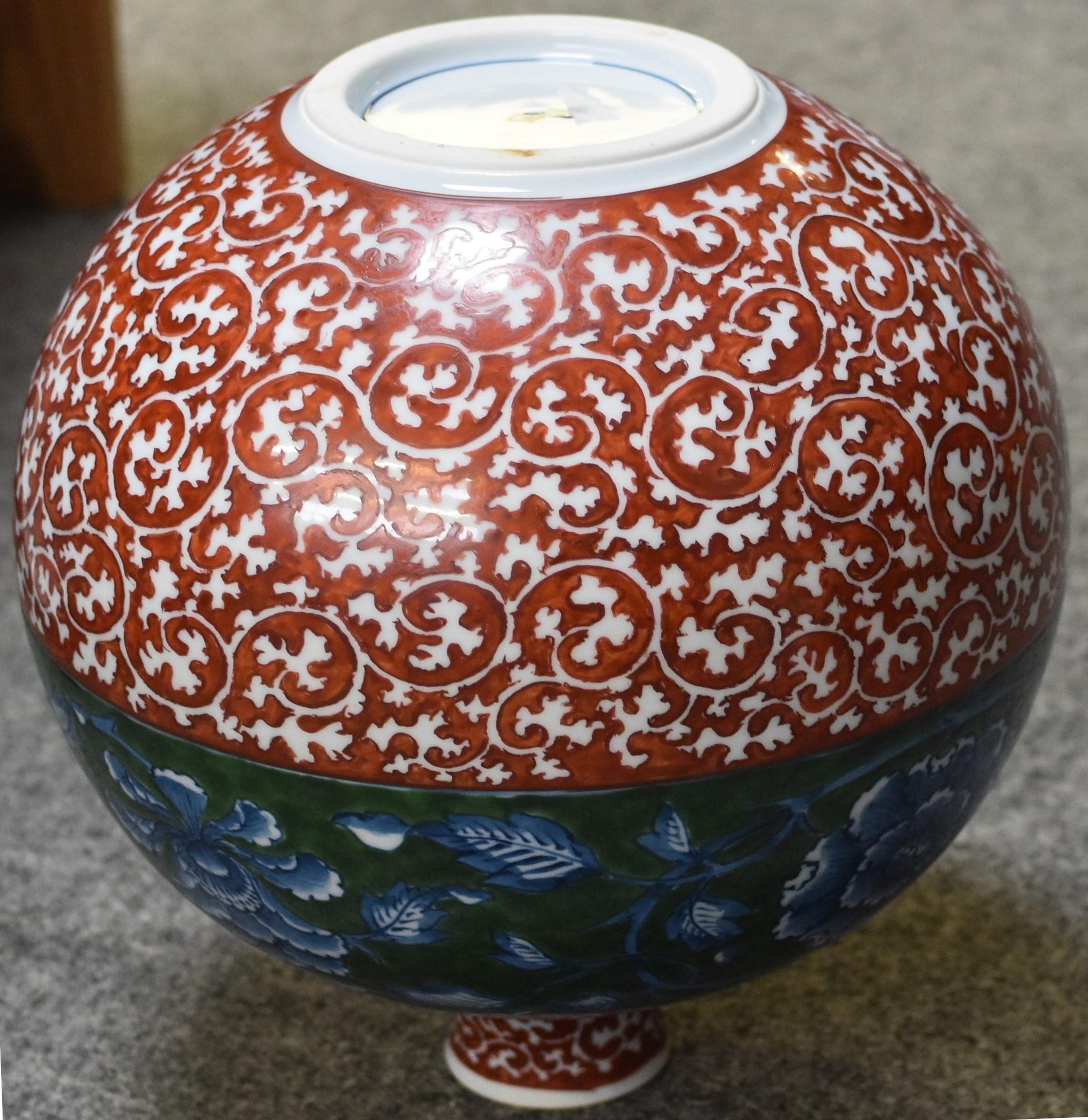 Die exquisite Vase zeigt ein verheißungsvolles traditionelles Arita-Arabesken- oder Karakusa-Muster in tiefem Rot. Dazu hat der Künstler ein breites grünes Band mit kühnen Blumen unter der Glasur hinzugefügt, das die Eleganz dieses auffälligen