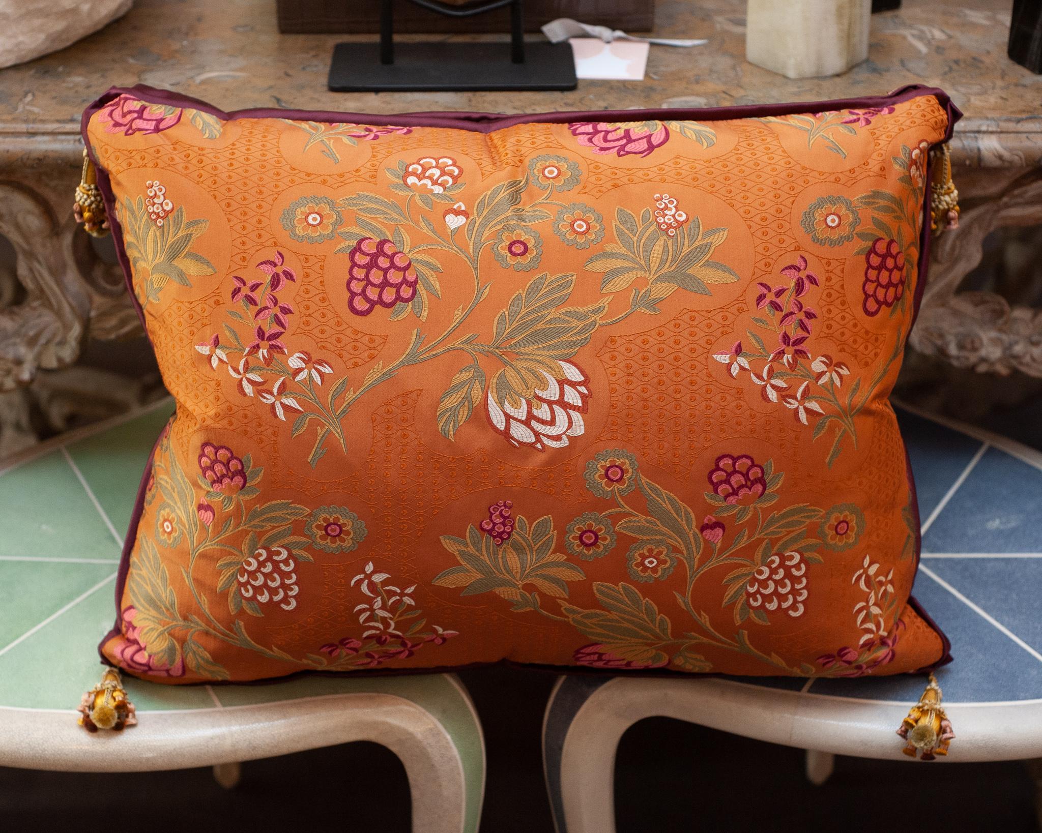 Un magnifique oreiller contemporain en brocart de soie rouge-orange avec des fleurs tissées, une bordure en satin de soie, un support en velours de soie et des glands ornés aux quatre coins. Cet oreiller de fabrication luxueuse est rempli de duvet