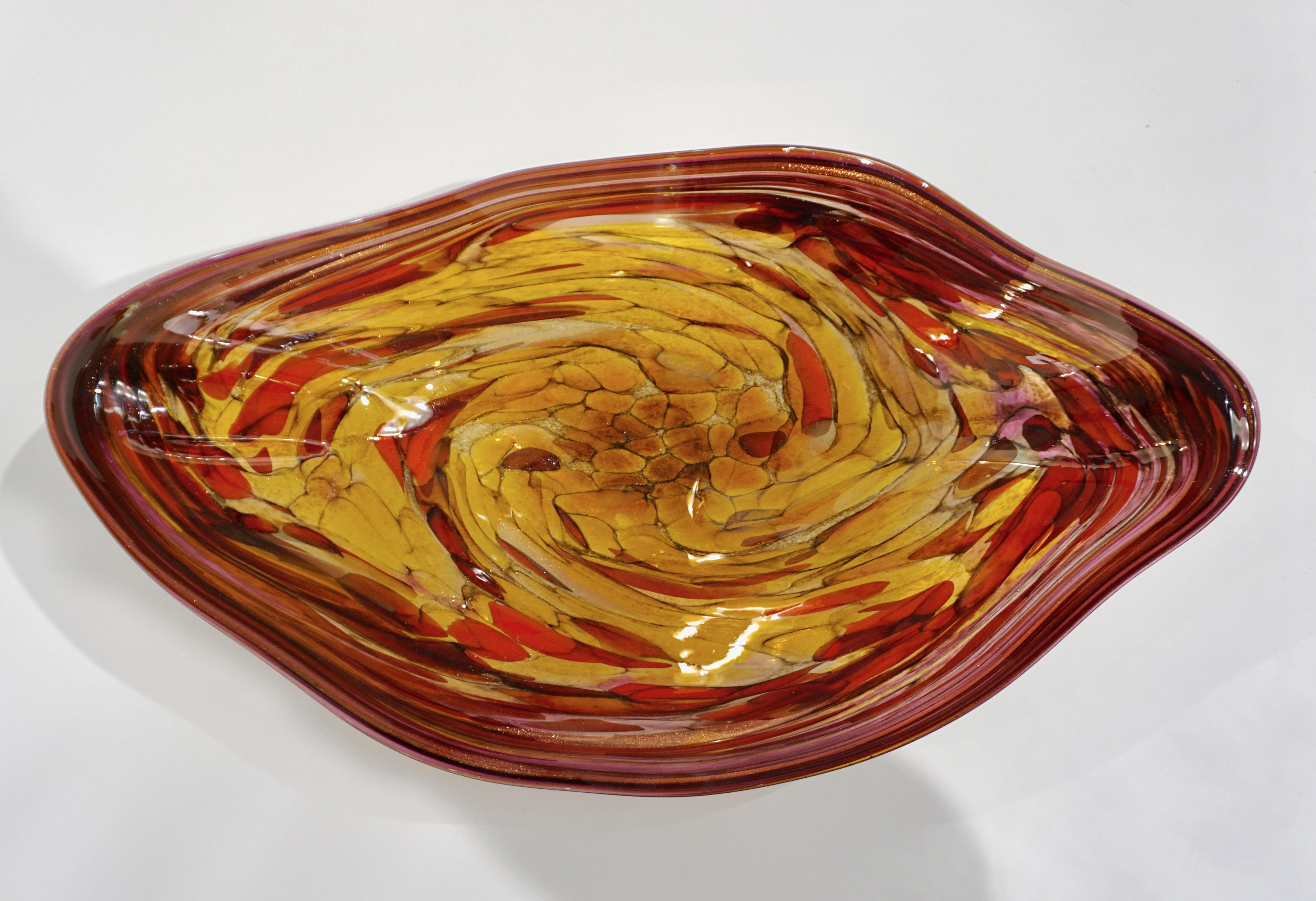 Contemporary American Art, a free form centerpiece/bowl, with a sensual waved shape glass blown like a modern painting, with an abstract design of strokes in red, pink, plum burgundy, yellow, amber, gold tints, made precious with glittering