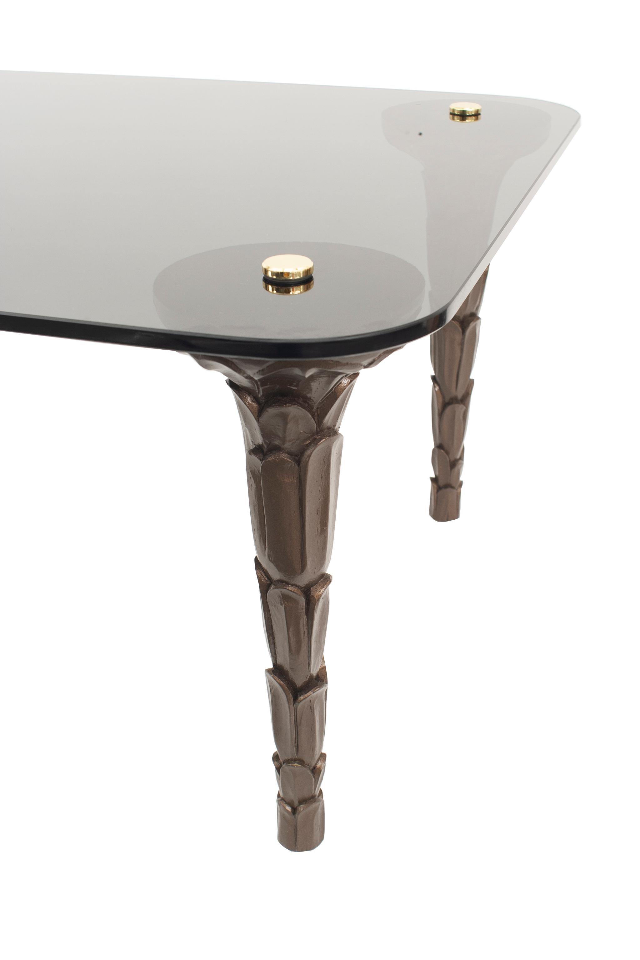 Contemporary Regency style coffee table with dark grey carved palm legs and smoked grey glass top secured with flat brass finials. 

Can be made custom size and colors.
   