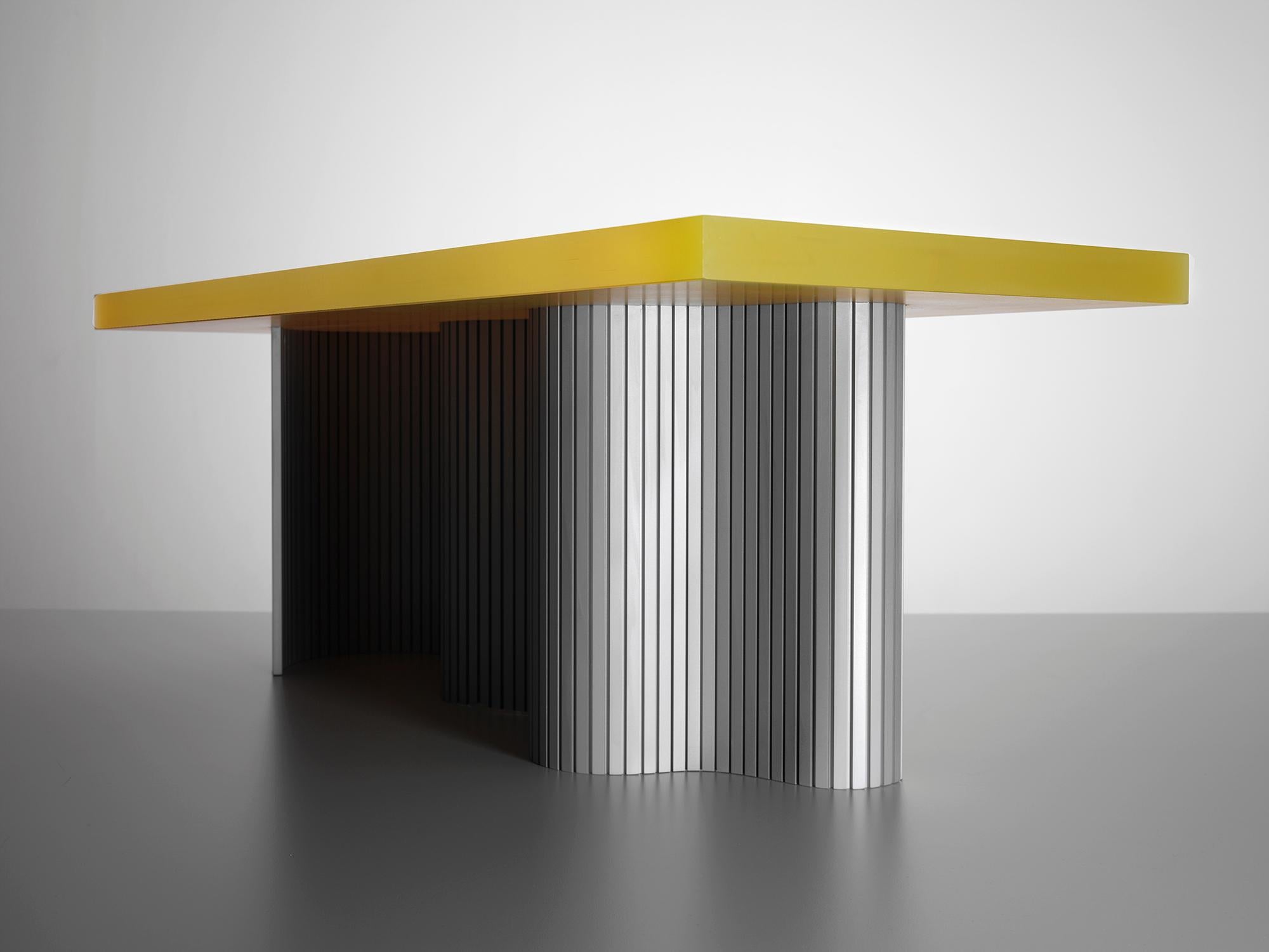 Spine table est une série de tables composées de deux éléments : une fine feuille d'aluminium emprisonnée dans une surface en résine moulée. Cette série est le résultat de nombreuses explorations matérielles concernant les formes courbes et la