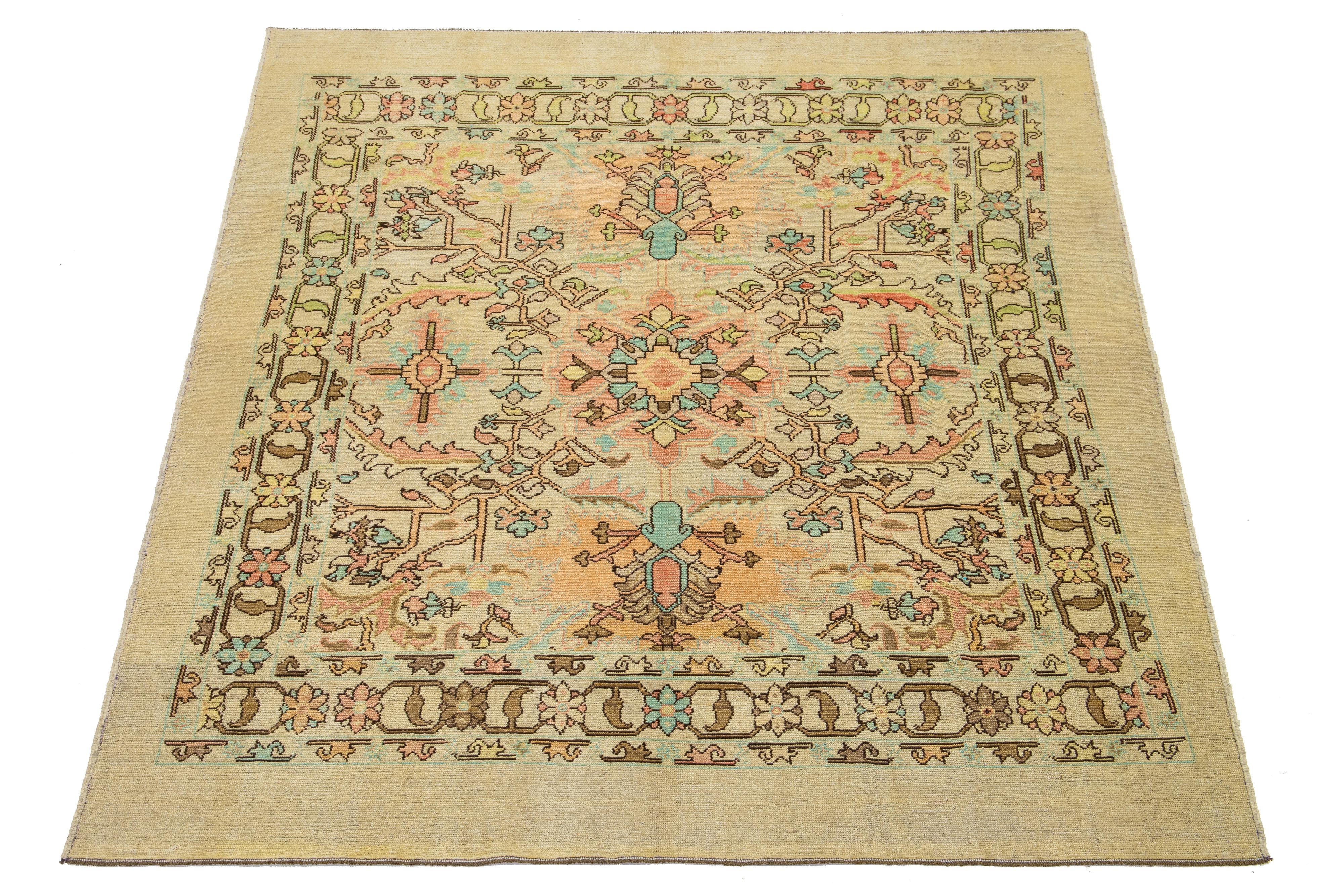 Gorgeous modern hand-knotted wool rug featuring a tan field. This Apadana Revival Collection rug showcases a stunning geometric, botanical floral design with teal, peach, brown, and yellow accents.

This rug measures 7'4