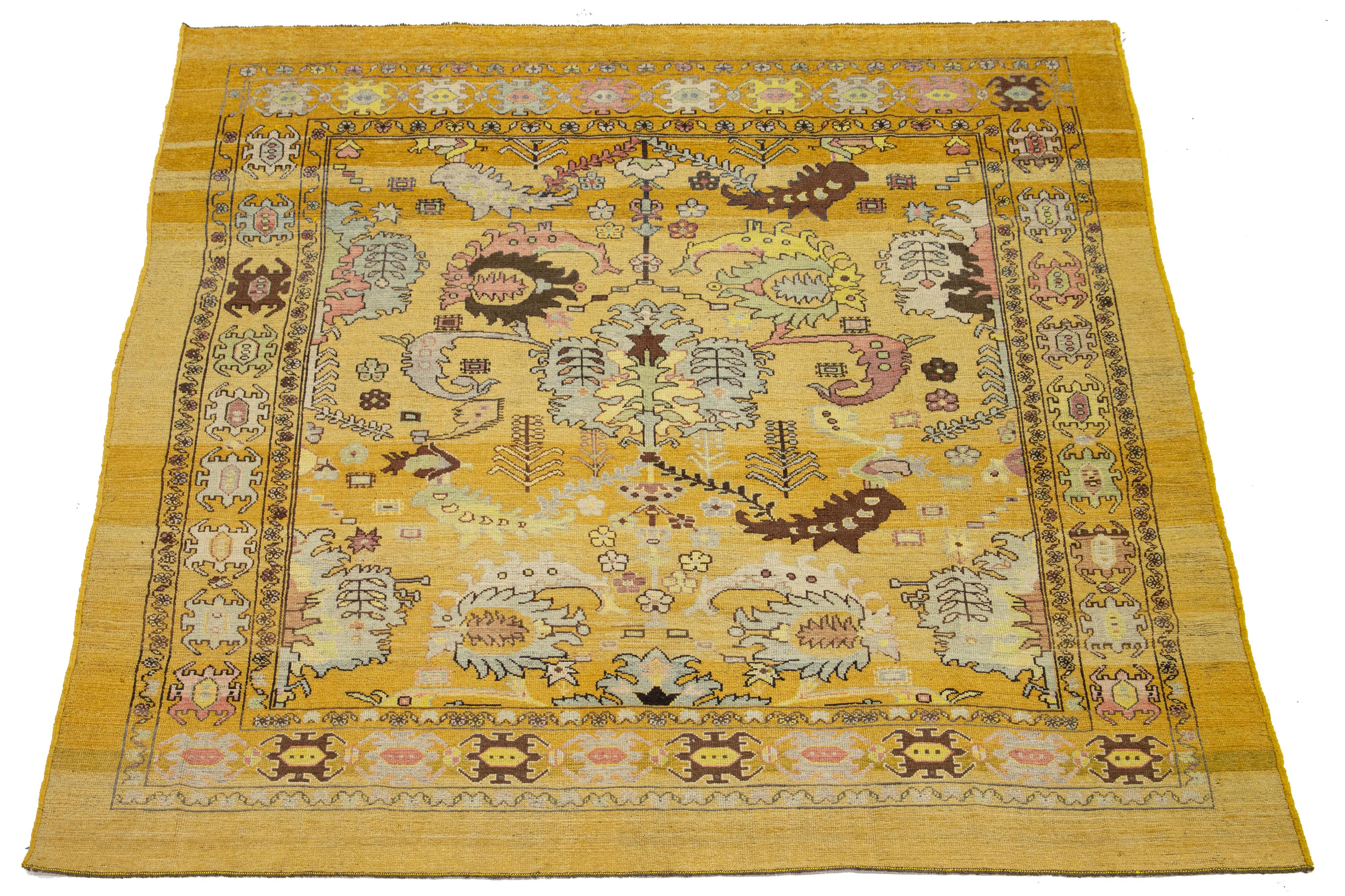 Gorgeous square modern hand-knotted wool rug featuring a yellow field. This Apadana Revival Collection rug showcases a stunning geometric, botanical floral design with green, pink, brown, and gray accents.

This rug measures 9'2