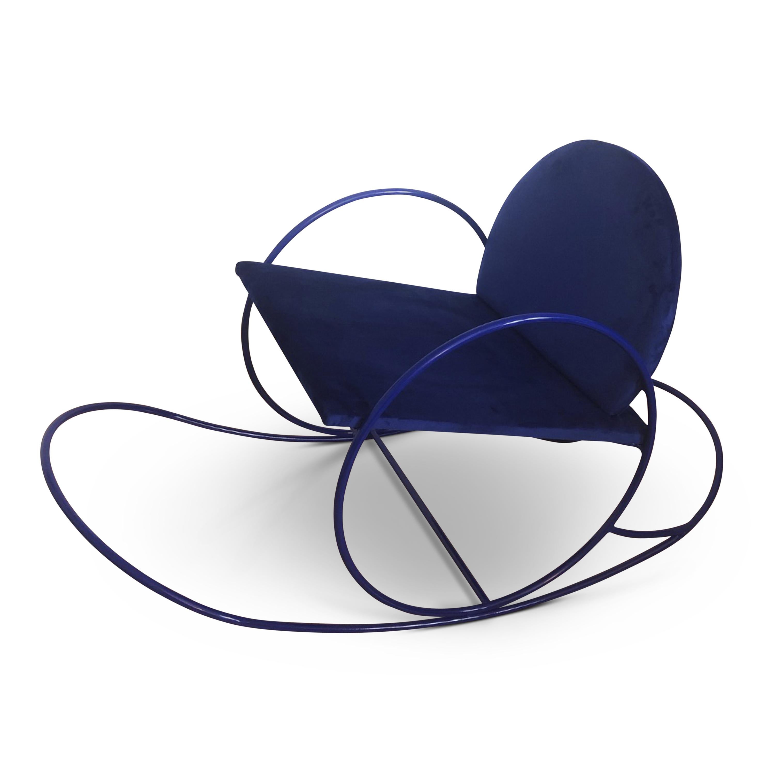 Der von Angel Mombiedro entworfene Sessel hat eine geschwungene Form, ein Metallgestell und eine mit dunkelblauem Samt gepolsterte Sitzfläche und Rückenlehne.
