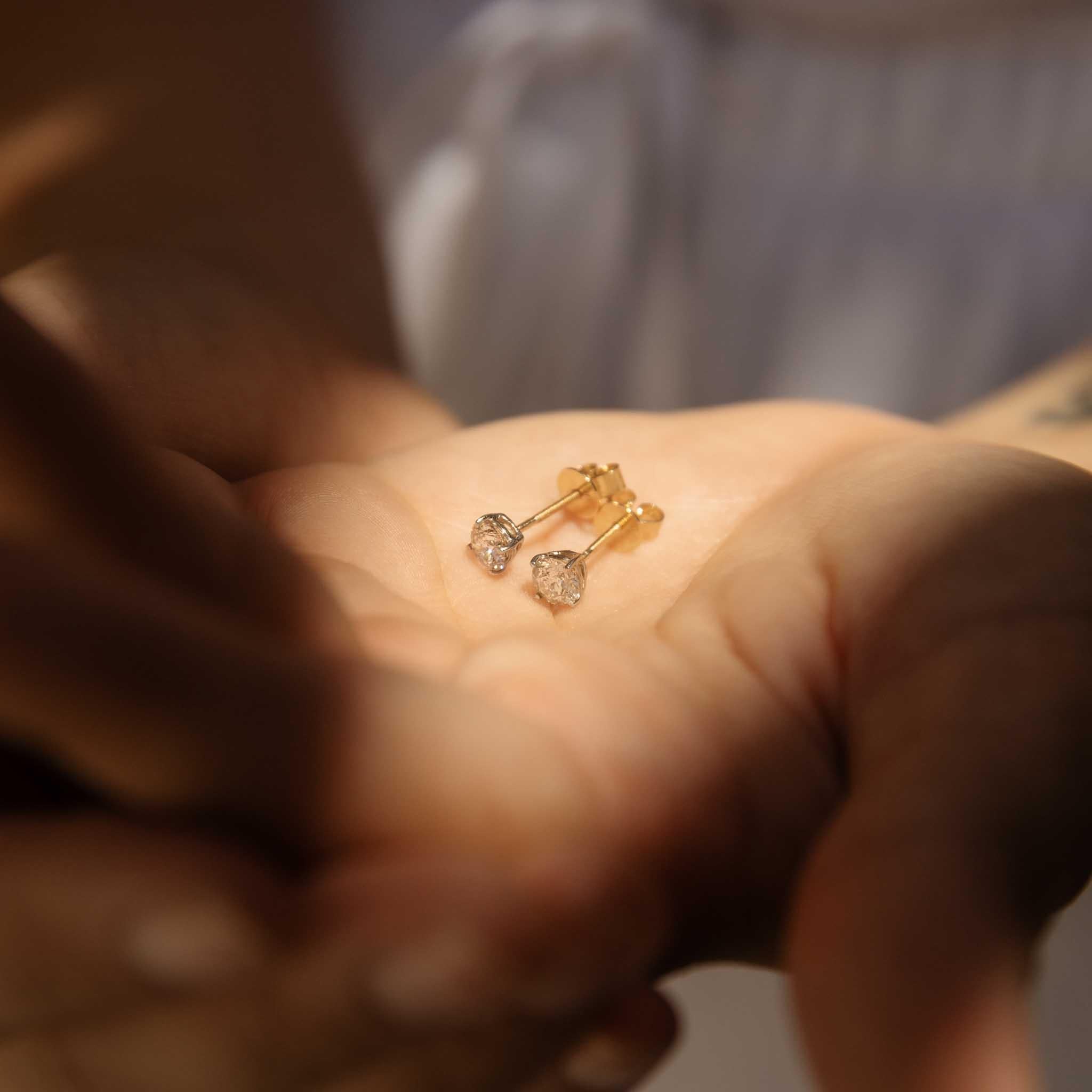 Our exquisite Phillida Earrings showcase a pair of brilliant-cut diamonds, their facets sparkling with a dazzling brilliance. The diamonds, set in a classic prong setting, are framed in 9 carat yellow gold. The earrings' elegant design exudes a