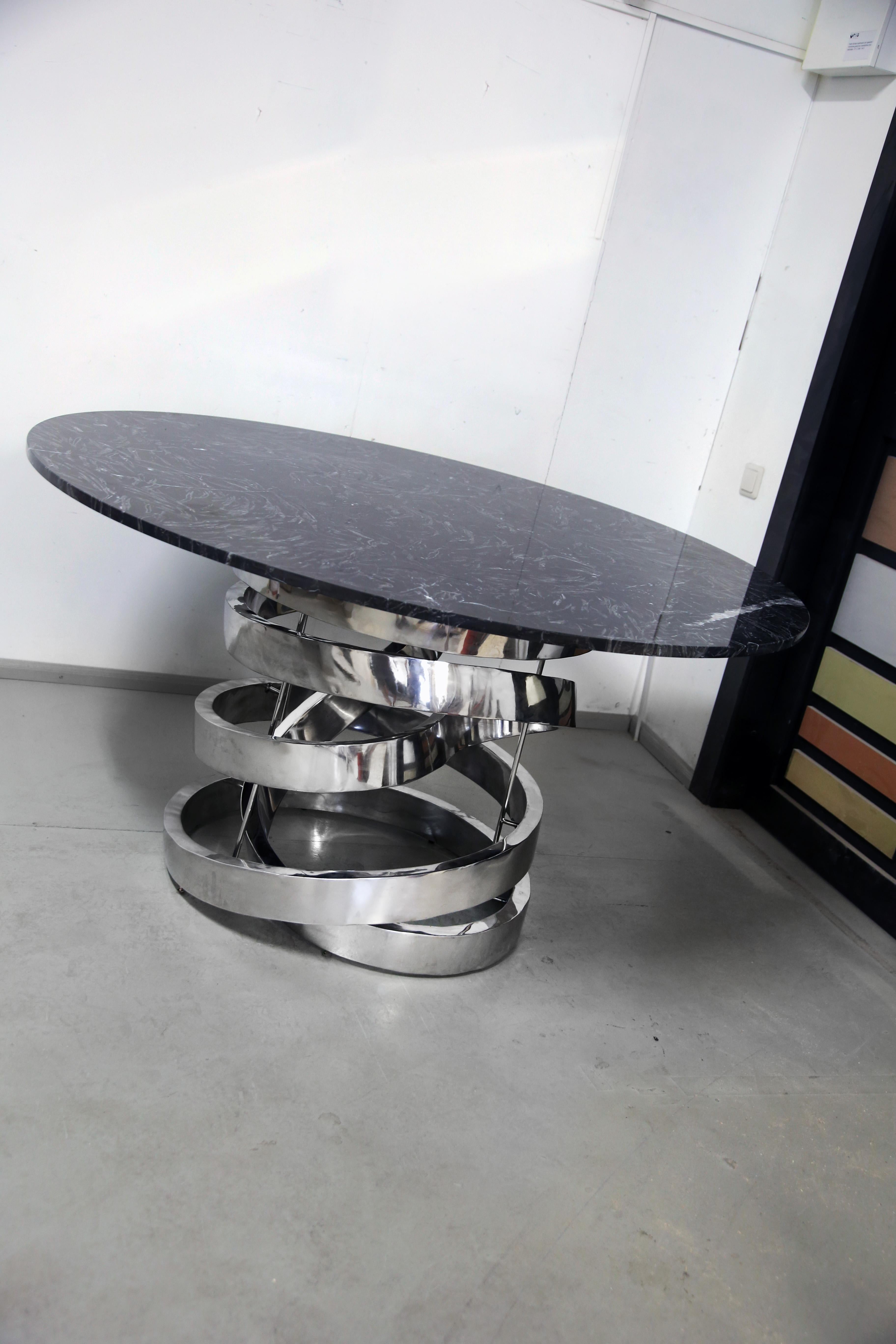 Introducing our stunning round dining table, crafted from premium black nero marble and featuring a polished stainless steel base in a unique and eye-catching shape. This table is not only functional, but also a true work of art that will elevate