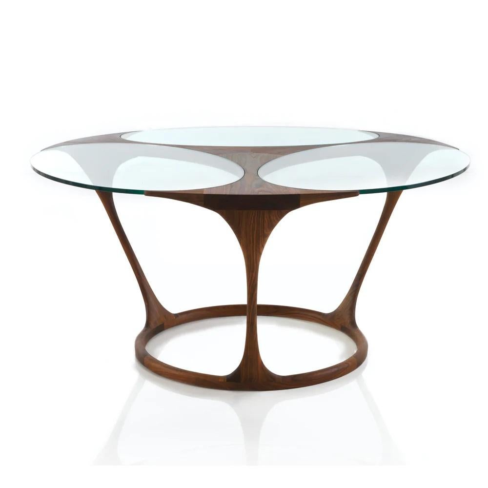 Handcrafted of Ash wood and thick crystal glass. This round dining table use closed structures in the lower part. This allows two things: high rigidity and extreme thinness in their limbs. The structure embraces the crystals without strangling them.