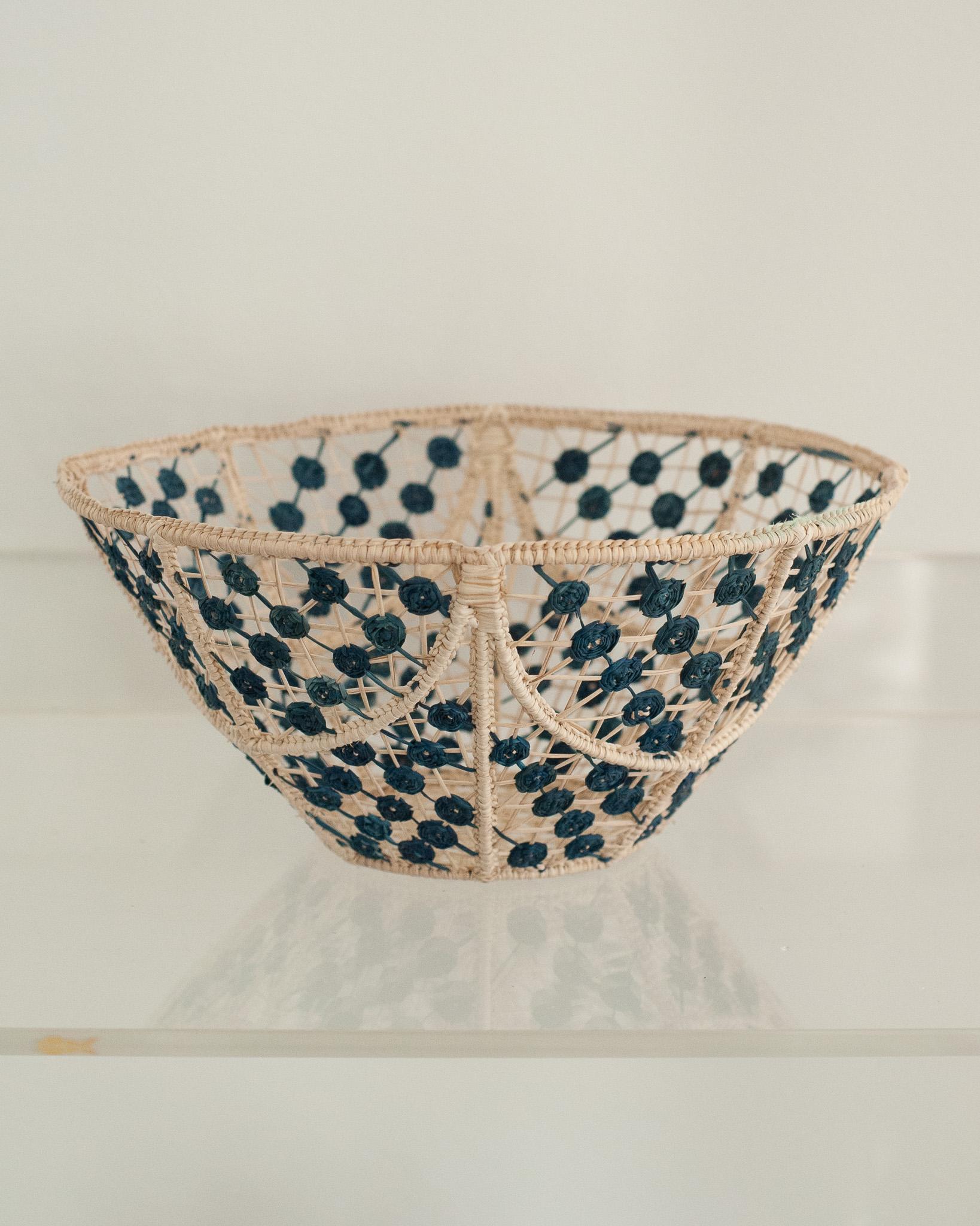 Verschönern Sie Ihren Tisch mit dieser atemberaubenden runden, handgeflochtenen Rattanschale mit navyfarbenen Knoten. Dieses von erfahrenen Kunsthandwerkern gefertigte Stück zeigt die klassische Technik des Webens auf moderne Weise. Von Jean Michel