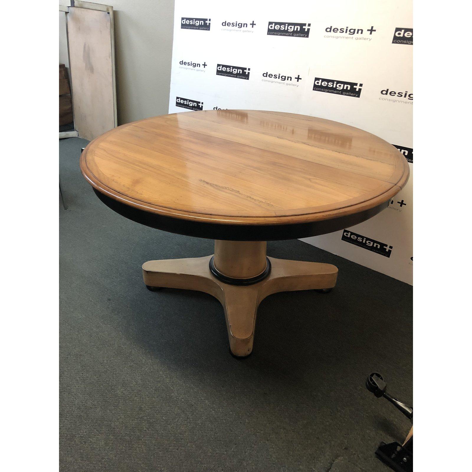 a contemporary dining table. A modern update on a Classic pedestal table, this piece is highlighted with varying stains. A natural stain allows the woodgrain to show through on the minimally beveled top surface, while a white wash with distressed