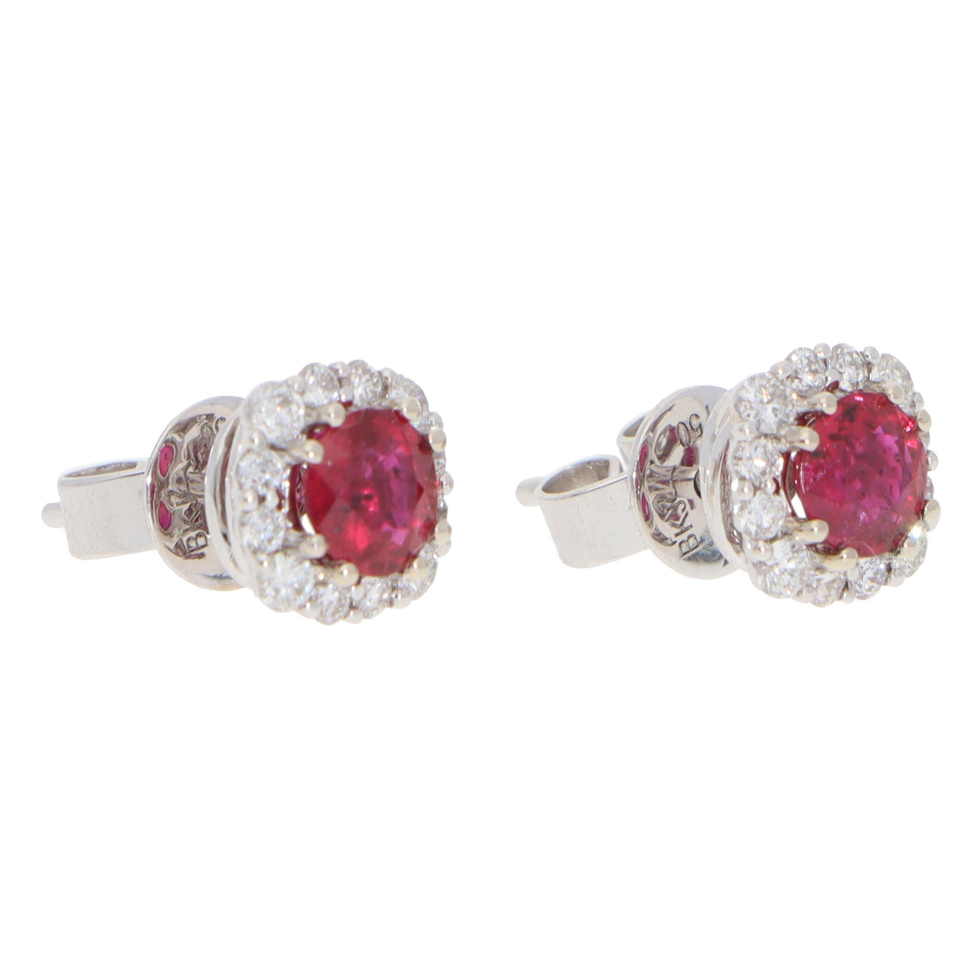 An elegant pair of contemporary ruby and diamond cluster stud earrings set in 18k white gold.

Each earring depicts a cushion-shaped floral cluster motif centrally set with a vibrant ruby and surrounded by 12 round brilliant-cut diamonds. The
