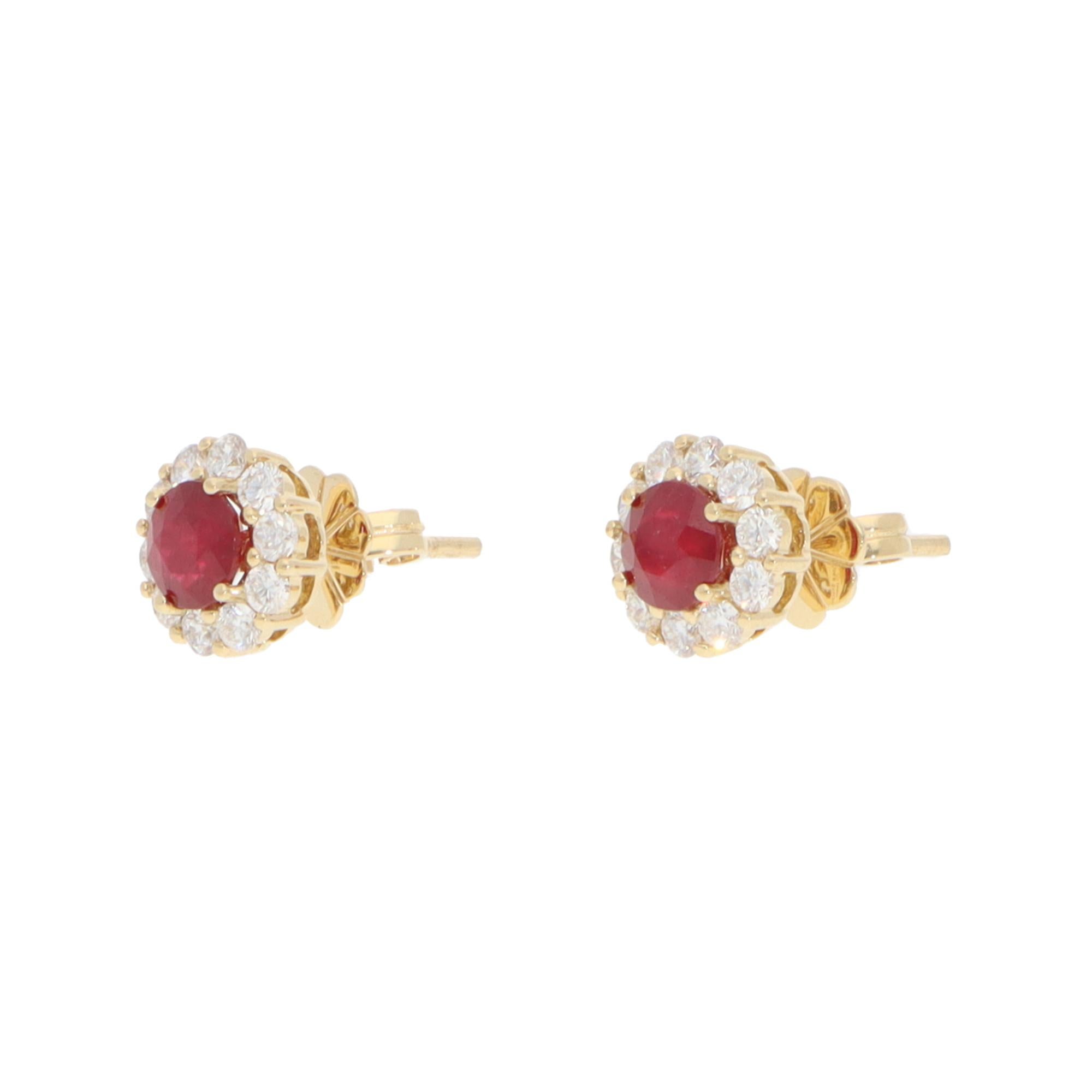 An elegant pair of contemporary ruby and diamond cluster stud earrings set in 18k yellow gold.

Each earring depicts a floral cluster motif centrally set with a vibrant ruby and surrounded by 10 round brilliant-cut diamonds. The earrings are secured