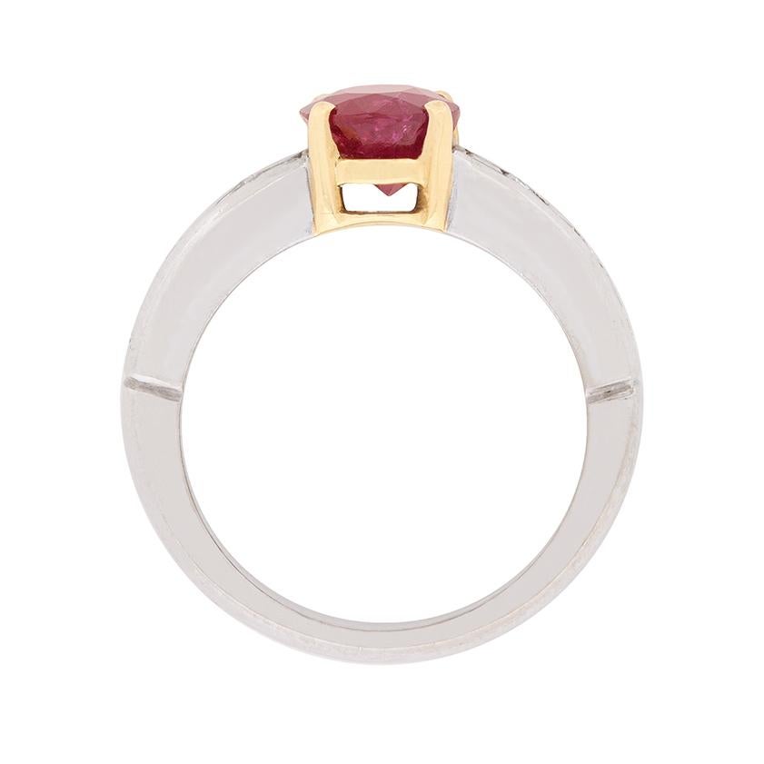 A gorgeous 1.50 carat oval-shaped ruby set in a four claw 18 carat yellow gold mounting is the star of this contemporary two-tone ruby and diamond ring.

A single graduating row of seamlessly set baguette cut diamonds gleams from each of the ring’s