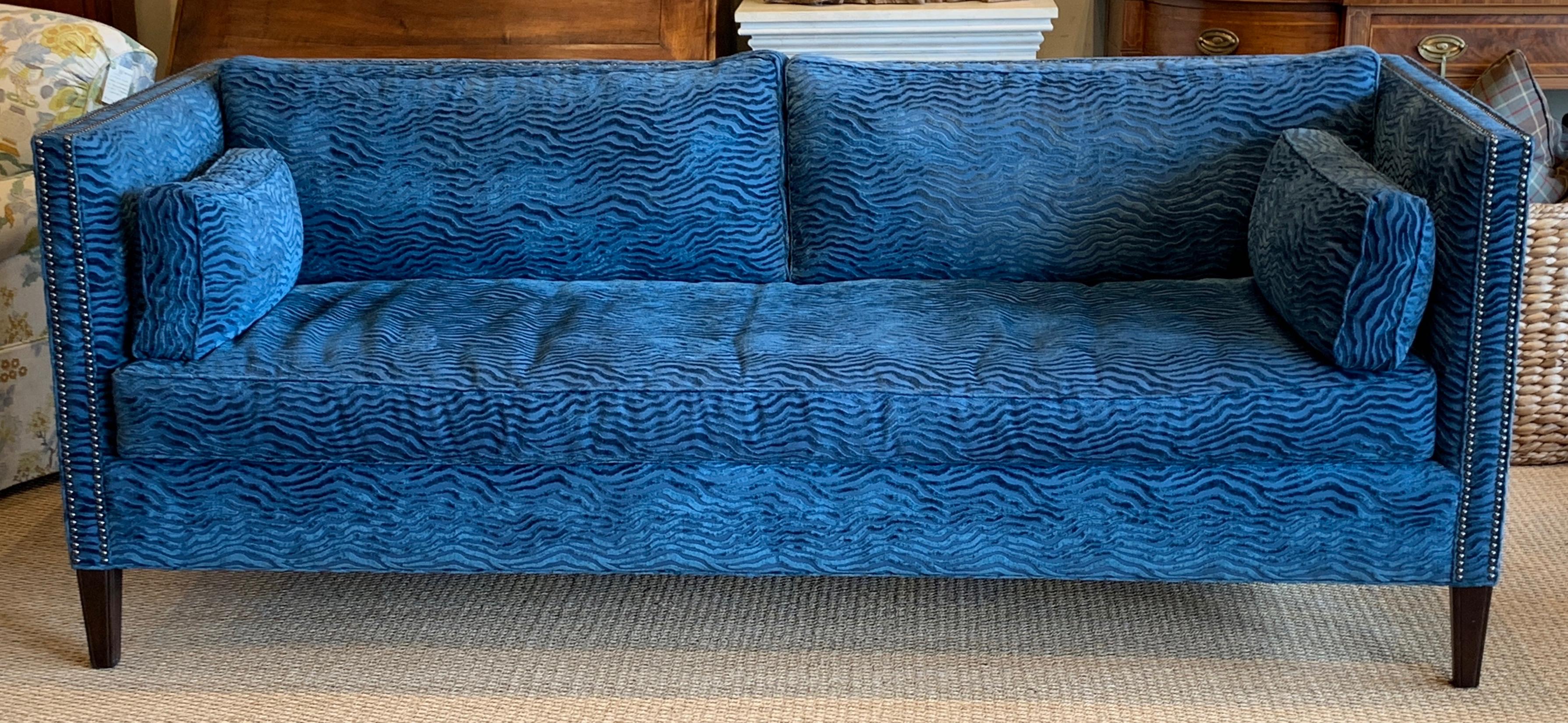 An elegant late 20th century sofa in a sapphire blue sculpted velvet fabric accented with brass nail heads, single down-filled cushion and square tapering legs.