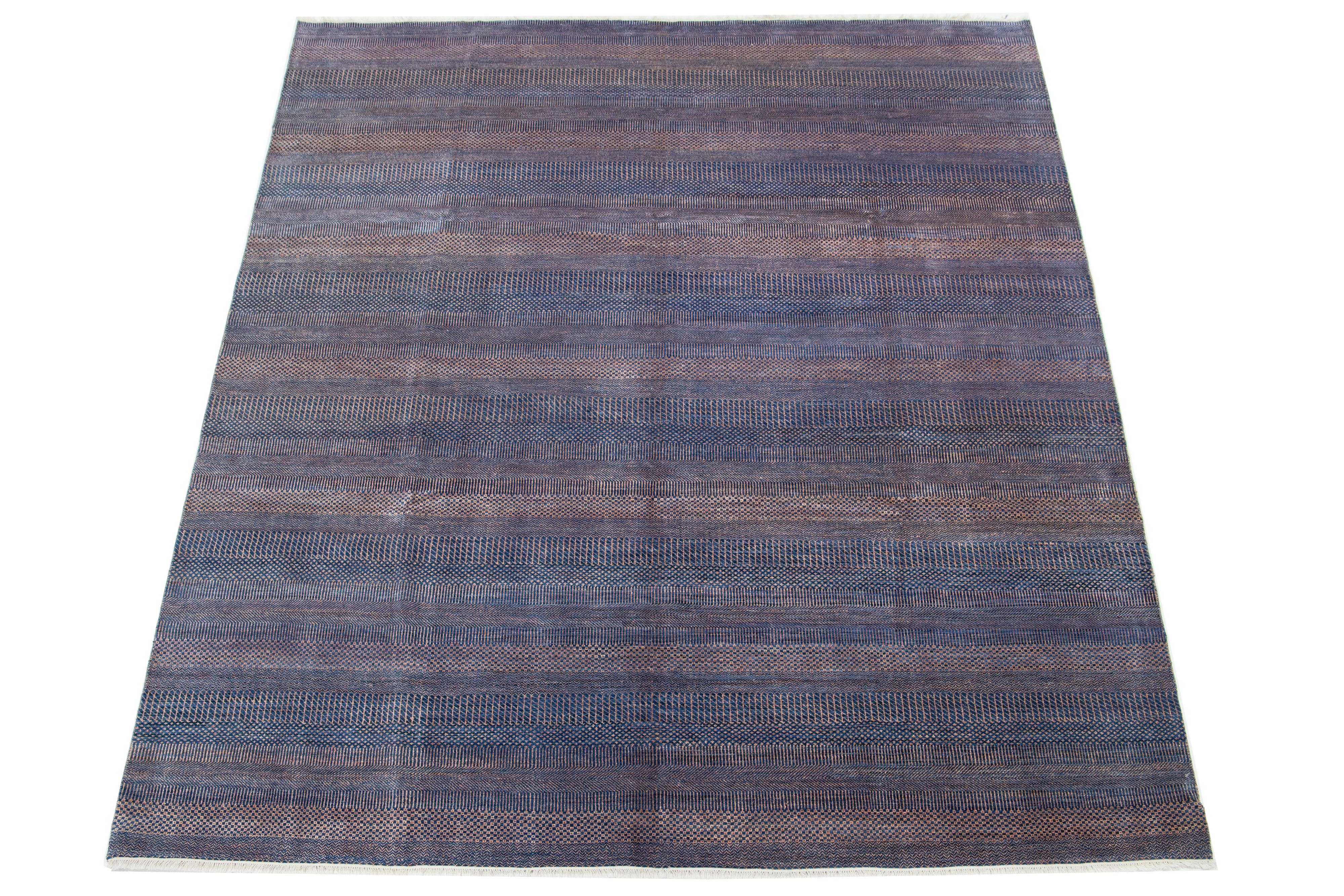 Ce tapis en laine noué à la main présente un design moderne en bleu, agrémenté de motifs géométriques complexes.

Ce tapis mesure 9'2