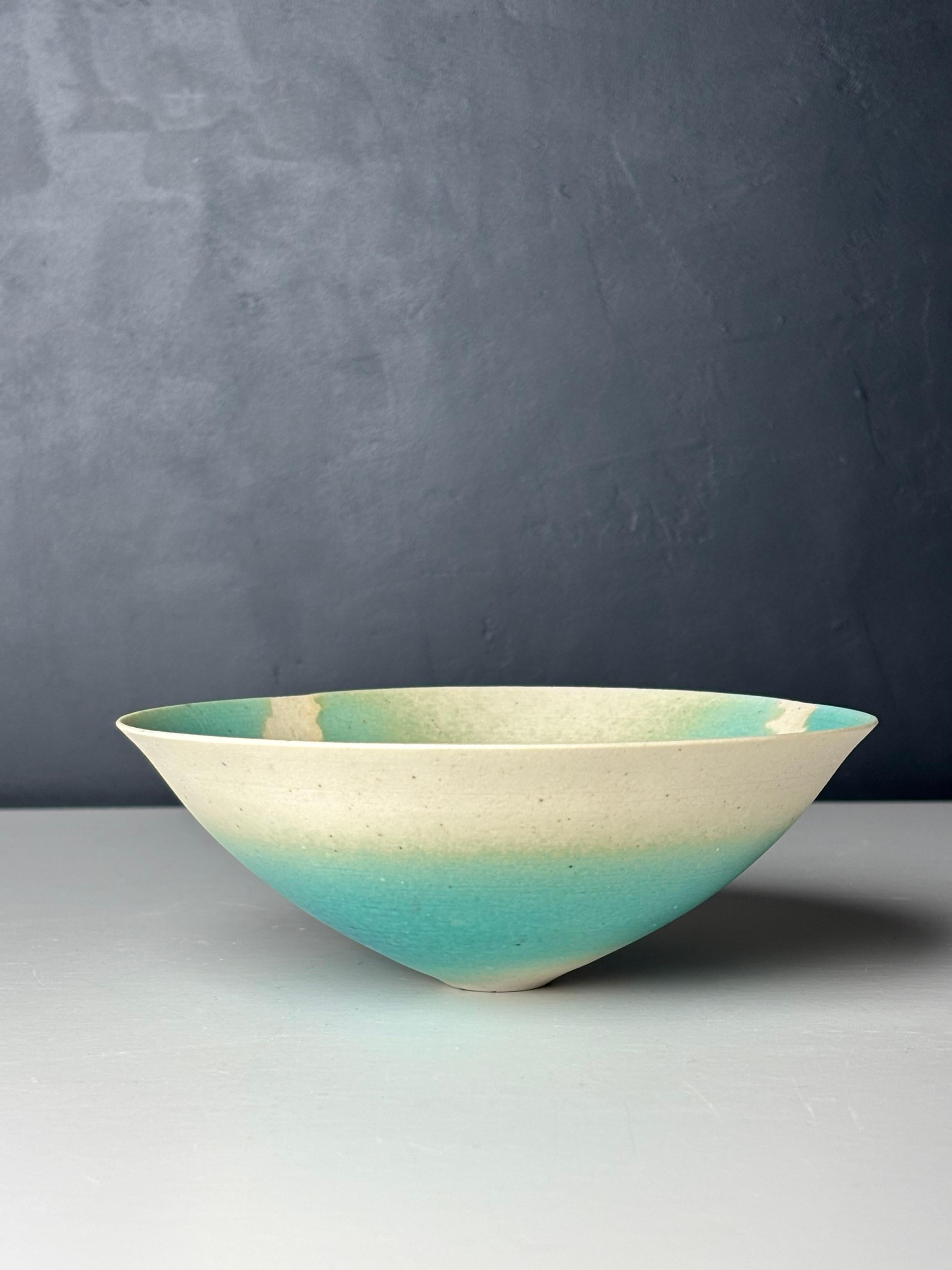Délicat petit bol scandinave en céramique organique moderne avec une glaçure mate de couleur turquoise et bleu aqua créant un motif graphique tourbillonnant en relief sur le matériau blanc. A utiliser pour le service ou comme vide-poche décoratif.