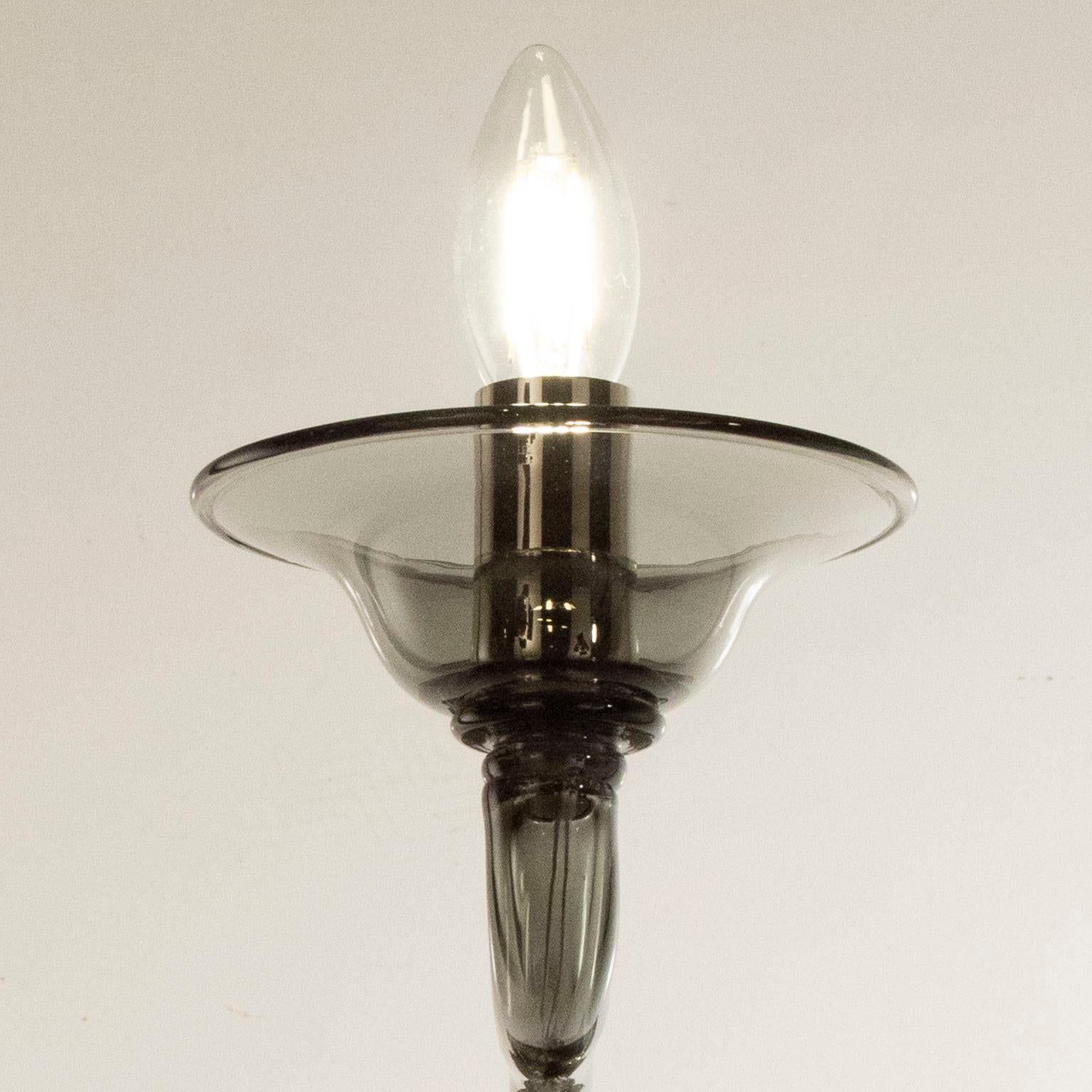 Multiforme Tobia sconce 1 lumière. Verre de Murano gris foncé lisse avec bras de château grimpant.
Le lustre en verre soufflé Tobia renvoie au design typique de la première moitié du 20e siècle.
Cette œuvre d'éclairage se caractérise par un élément