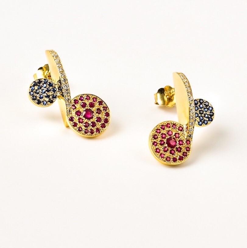 The 'Rolling Disk’ earrings are crafted in 18k gold, hallmarked in Cyprus. These impressive, super elegant, sculptural ear pieces, come in a highly polished finish and feature Rubies, 0,58 Cts, Blue Sapphires 0,40 Cts and White, VS Diamonds, 0,26