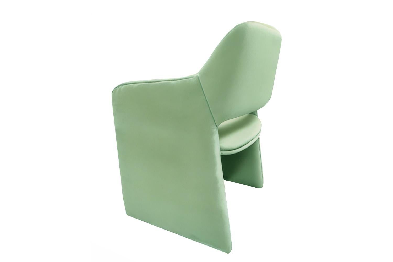 Der Alquimia Dining Chair aus aquamarinfarbenem Samt ist ein Gefäß der Verwandlung, in dem radikale Weichheit auf skulpturale Klarheit trifft. Mit seinen geschwungenen Armlehnen und den kühnen monolithischen Beinen schlägt dieser Stuhl eine Brücke