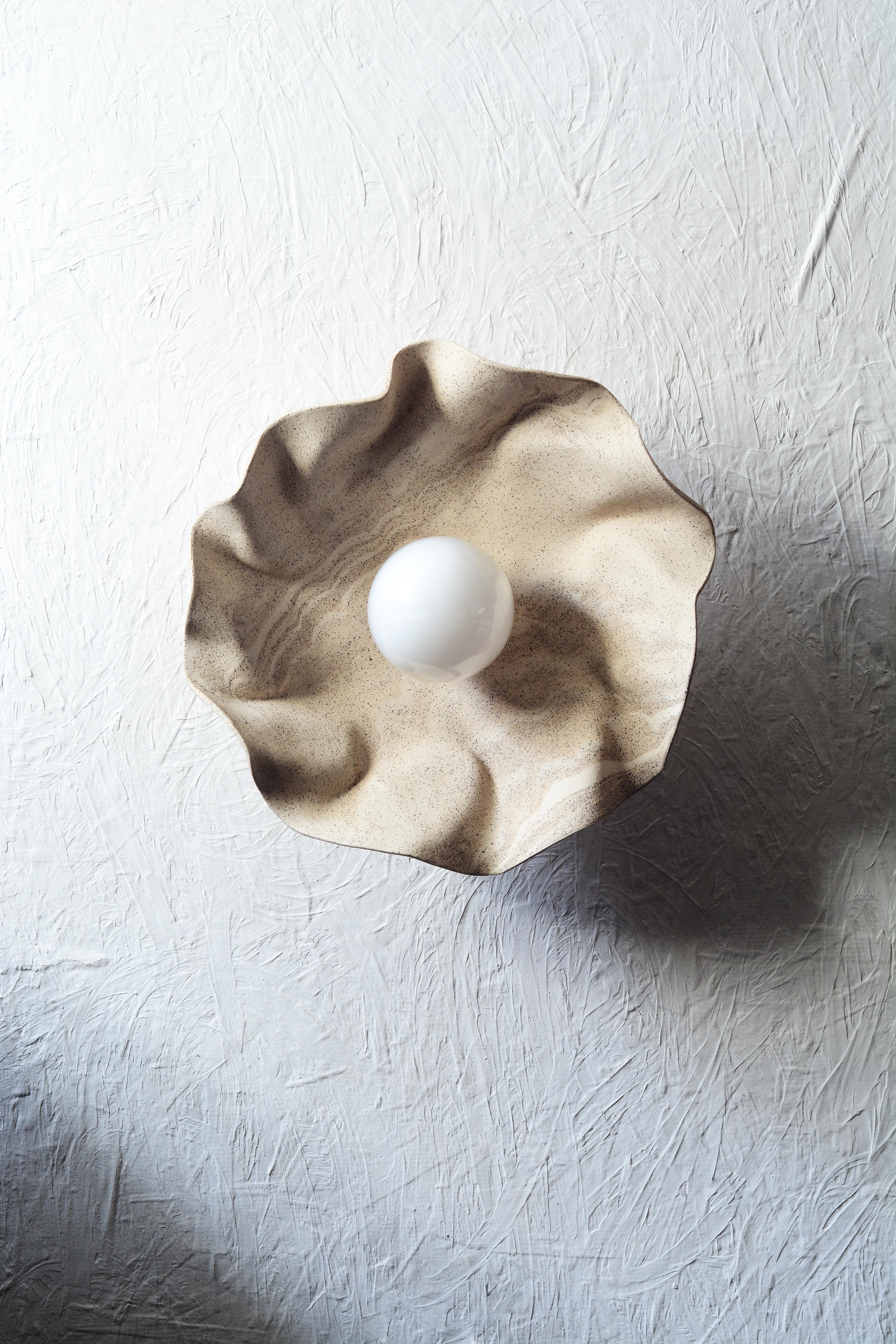 Handbuilt ceramic wall sconce with draped/folded marbled stoneware clay, reminiscent of the natural world.The nature of the technique used to shape the clay adds a touch of uniqueness to each piece.
The sconce features a distinctive design with