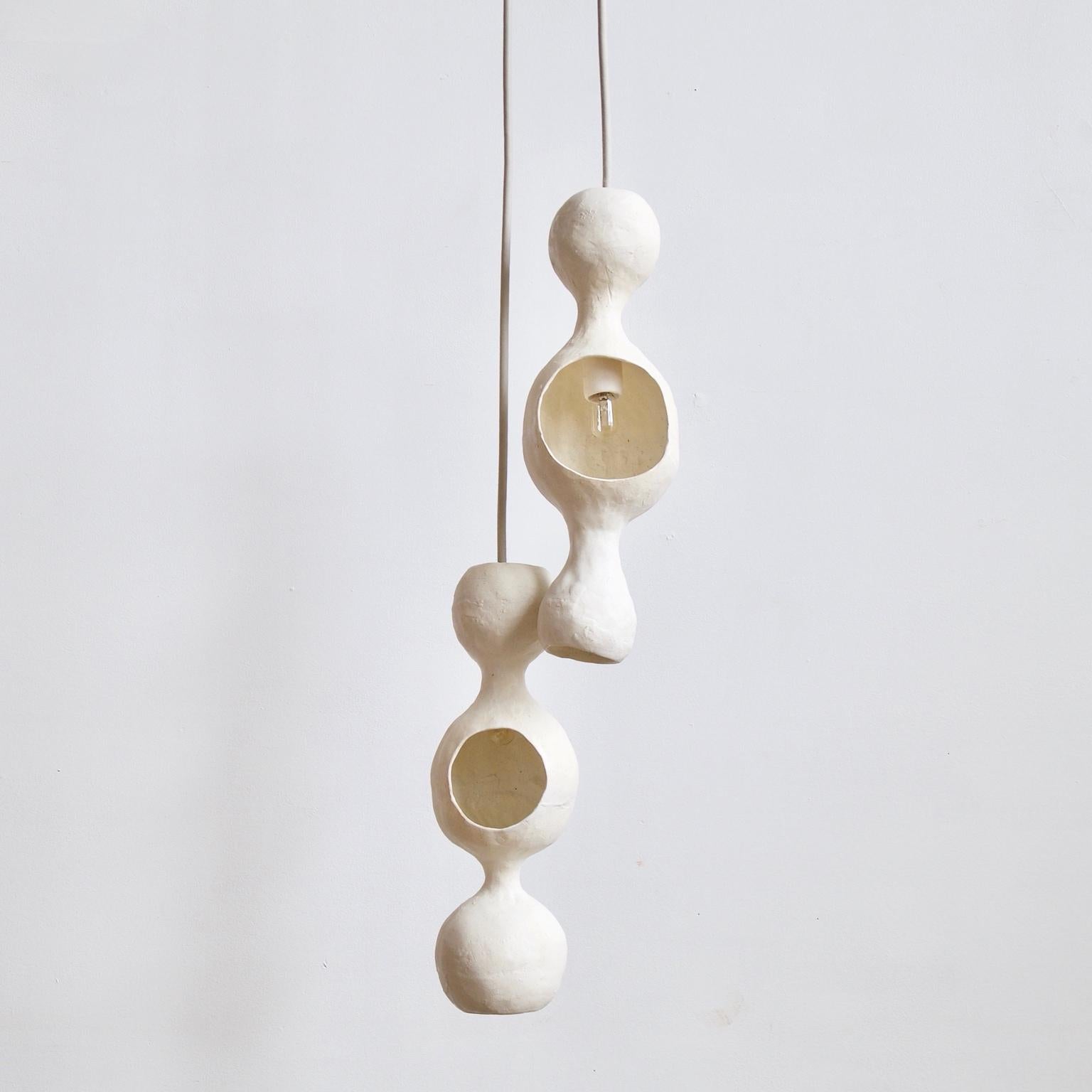 White Bowerbird couple ist eine zeitgenössische, handgefertigte, doppelschalige Hängeleuchte aus Keramik mit mattweißer Glasur, deren warmes Licht von einer runden, fröhlichen Form reflektiert wird. Jede Schale ist individuell von Hand geformt und