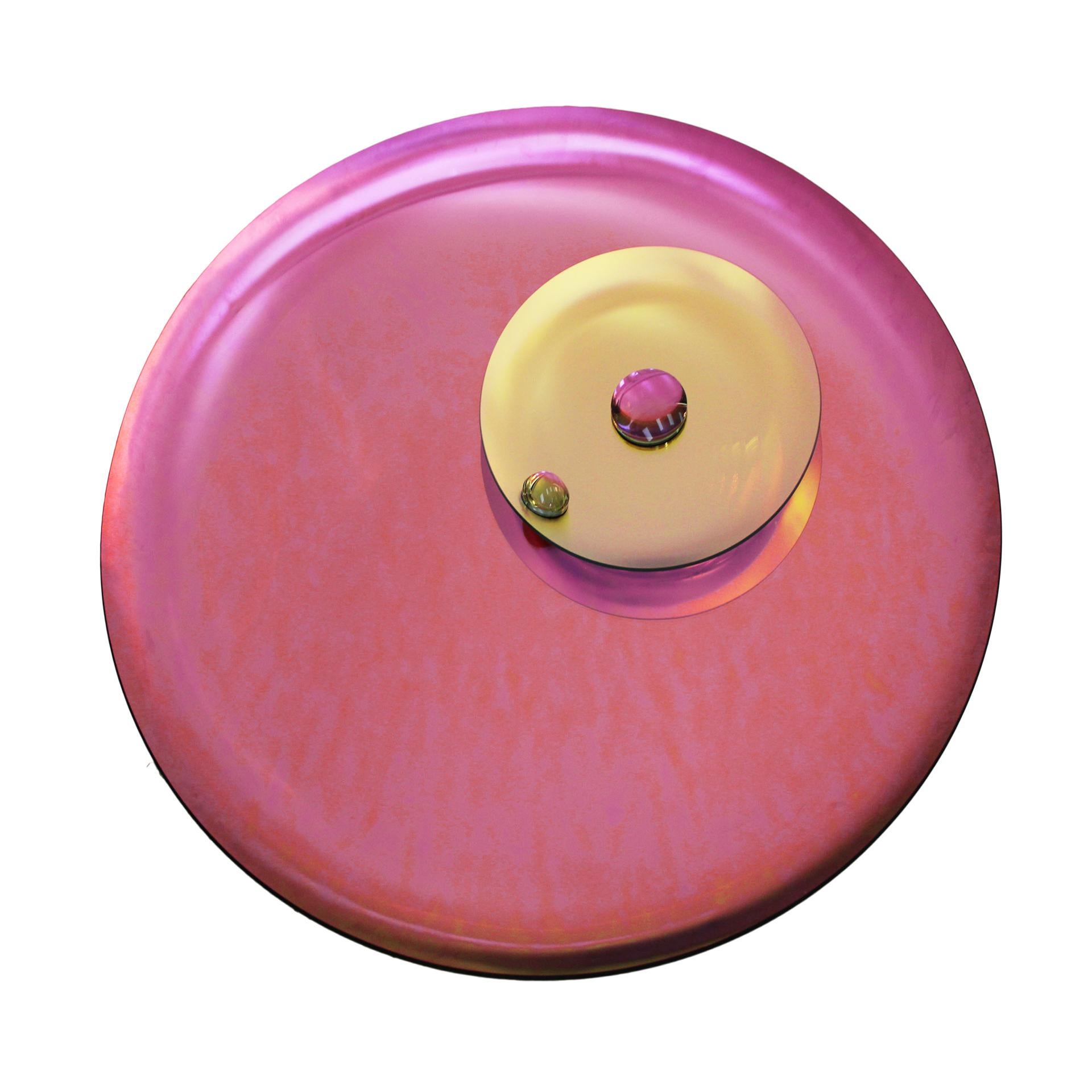 This modern sculptural French mirror features a concave design, handcrafted from pink molded glass and colored lenses. It serves as both a wall hanging artwork and a unique piece of functional decor, finished with bronze finial details for easy wall