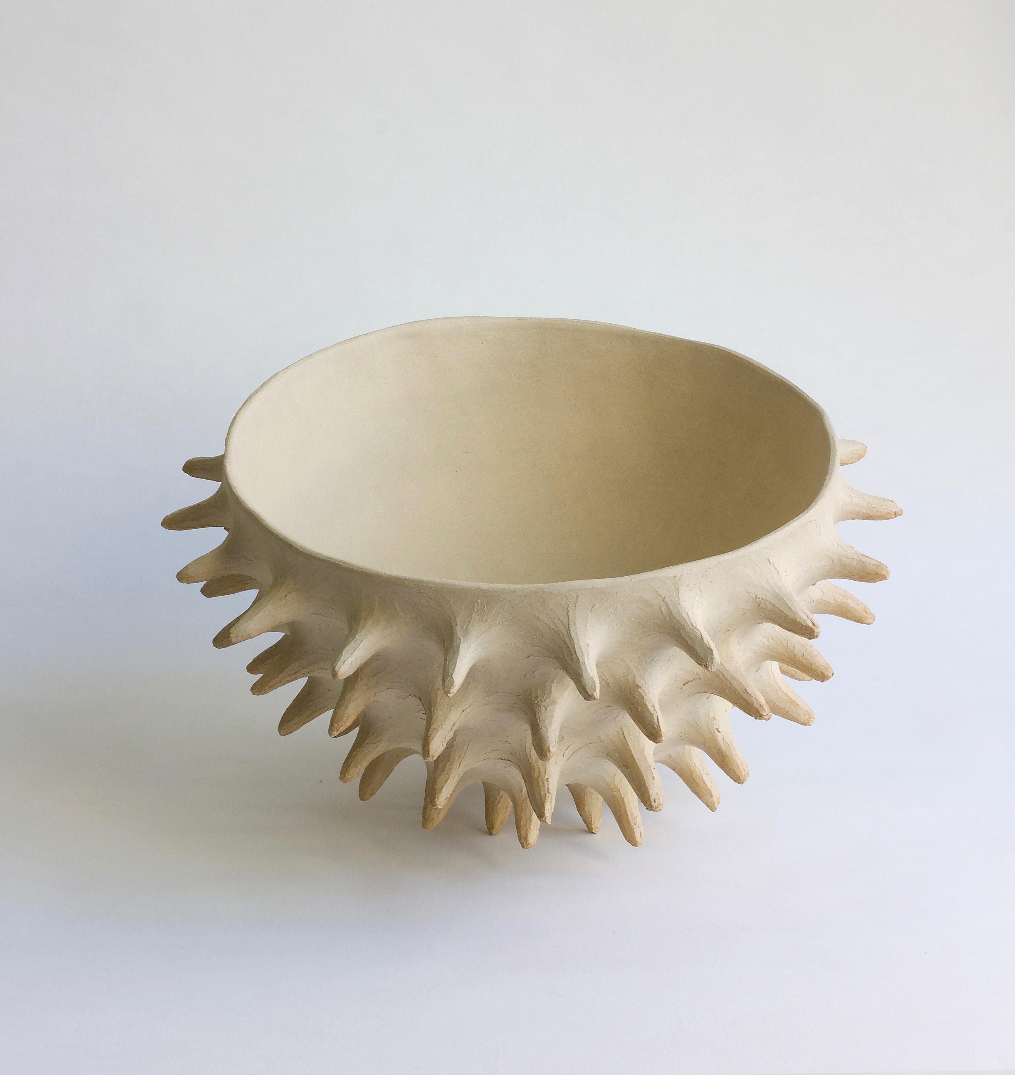 White brutalist ceramic bowl with urchin-like spikes. This sculpture is rich in light and shadow, with rusty tips, and a smooth inner surface. The artist patiently shapes the raw clay into bold, organic forms, where the mark of the sculptor is