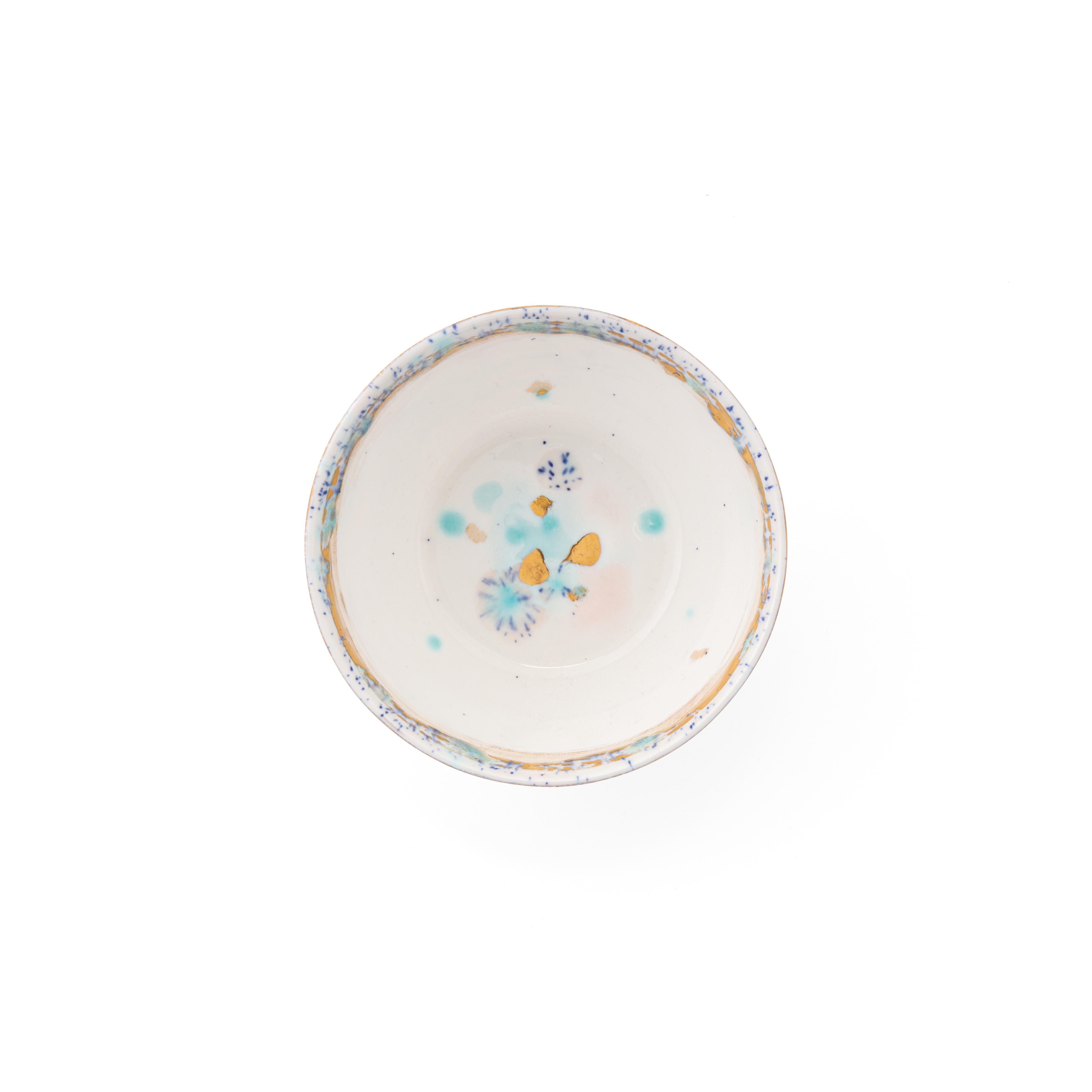 Hand painted in Italy from the finest porcelain, this Dafne Fruit Bowl has a narrow pink and blue dotted rim surrounding a broad, delicate golden decor of stylized flowers, the center is white with subtle light blue, pink brushes and golden dots