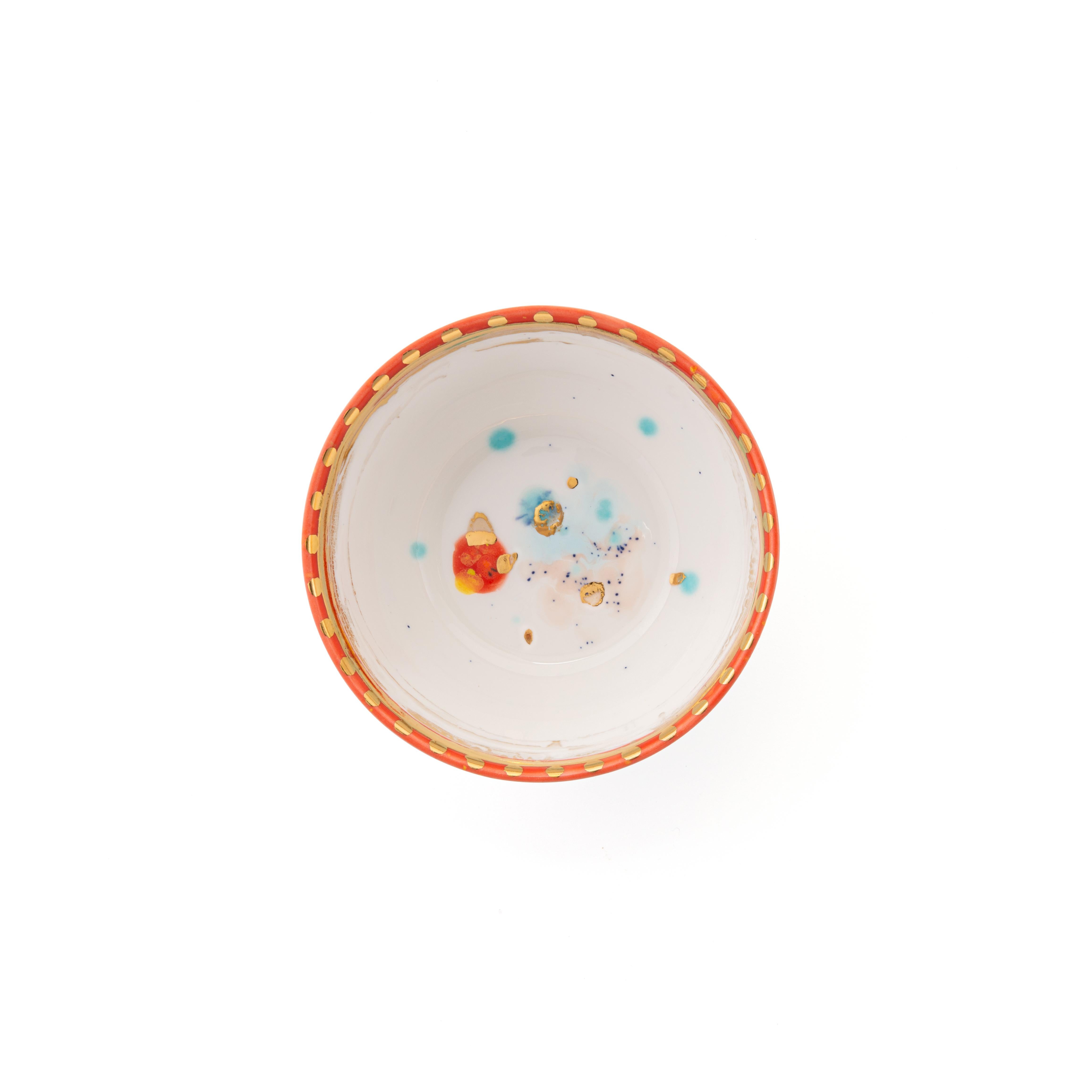 Hand painted in Italy from the finest porcelain, this Scipione fruit bowl has the rim sprinkled with a light decor of golden dots and thin circles; all around the edge, a narrow, African red rim, punctuated with golden dots; at the center very