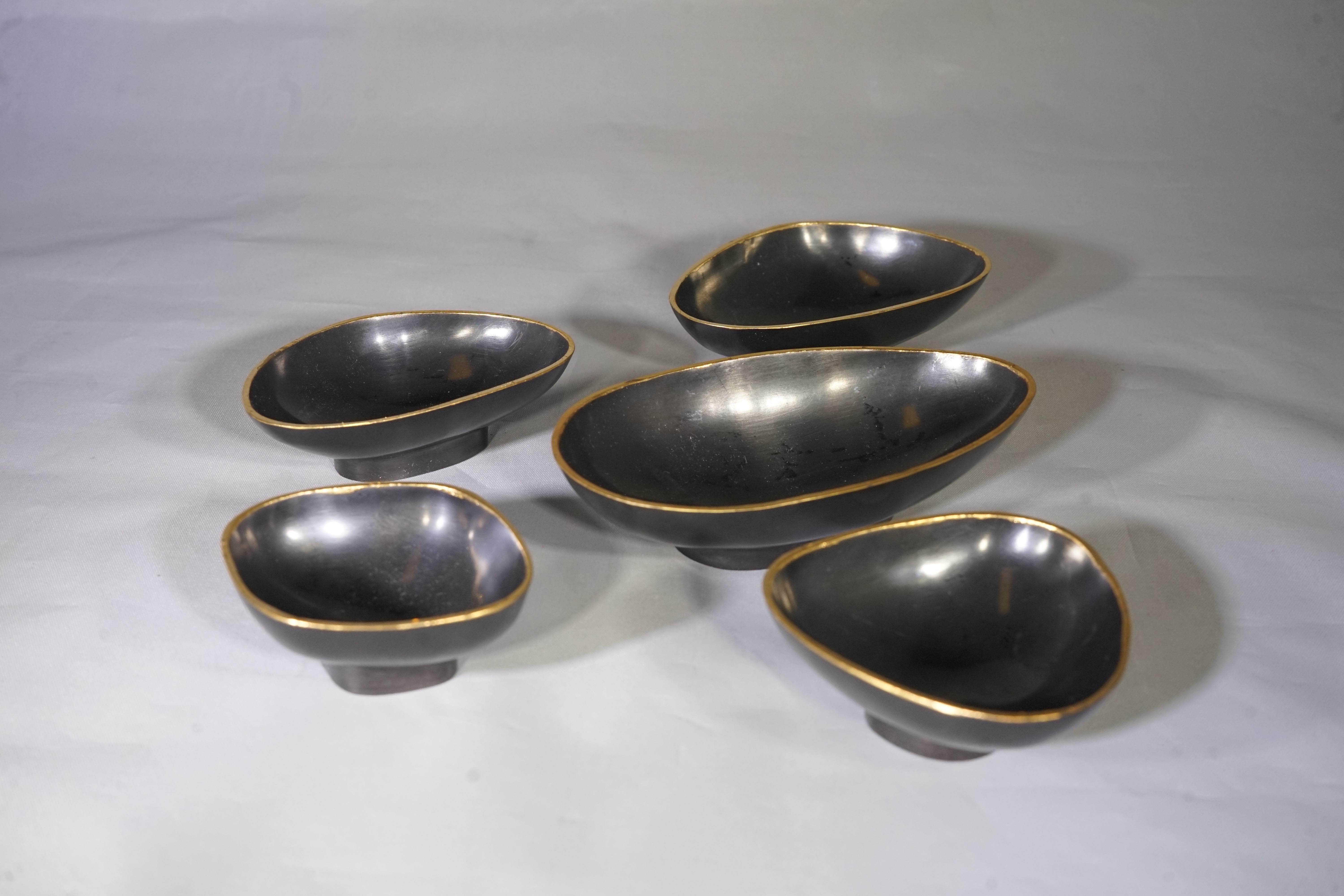 Contemporary set of five black decorative mini bowls featuring irregular shapes and bronze-edged detailing.